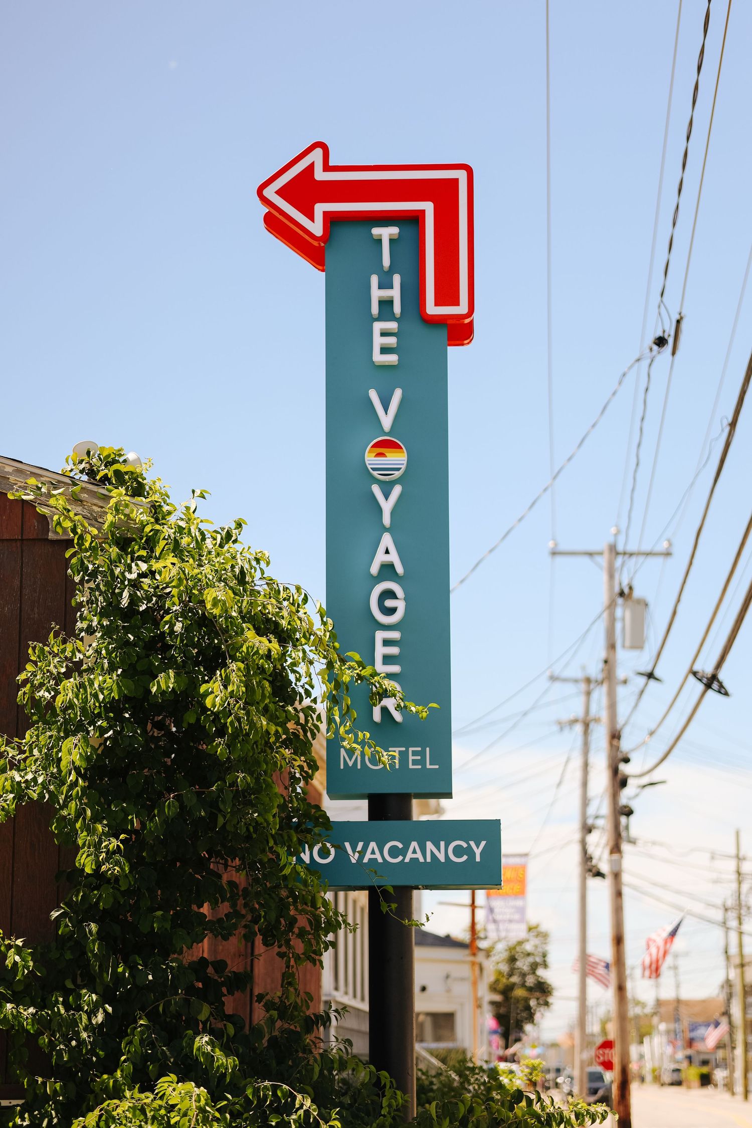 Vintage motel sign with red arrow against bright blue sky, photographed for hotel marketing in Maine