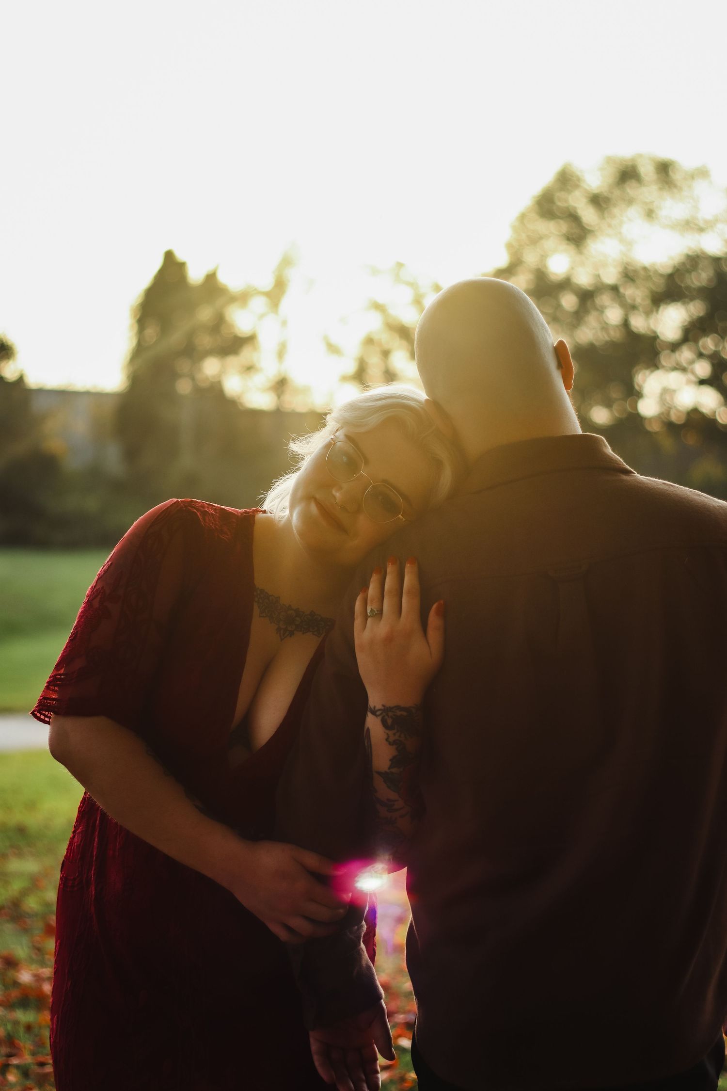 A romantic couple's silhouette against a glowing sunset in a park setting.