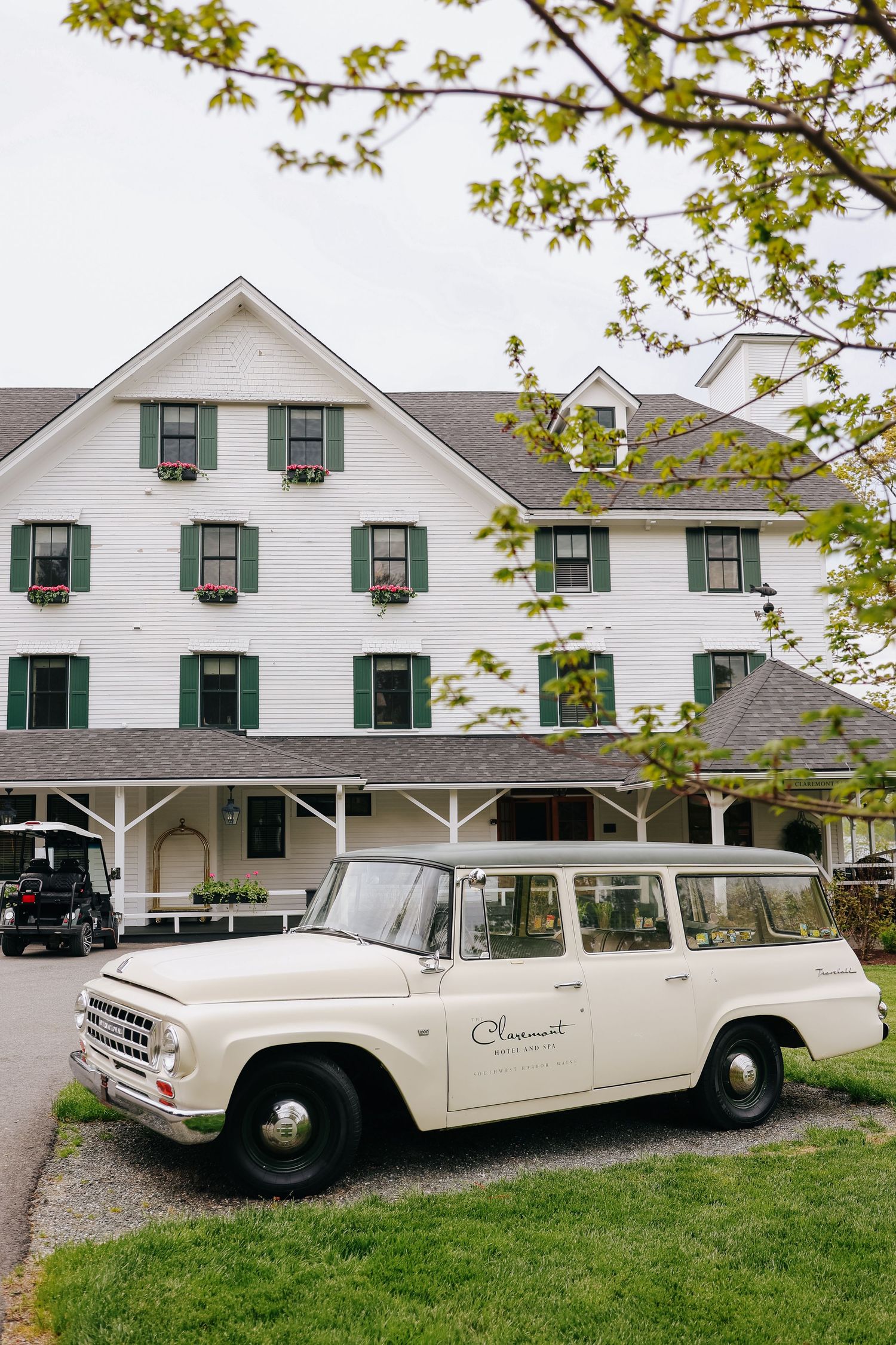 Vintage cream International Harvester wagon parked outside a white New England inn with green shutters.