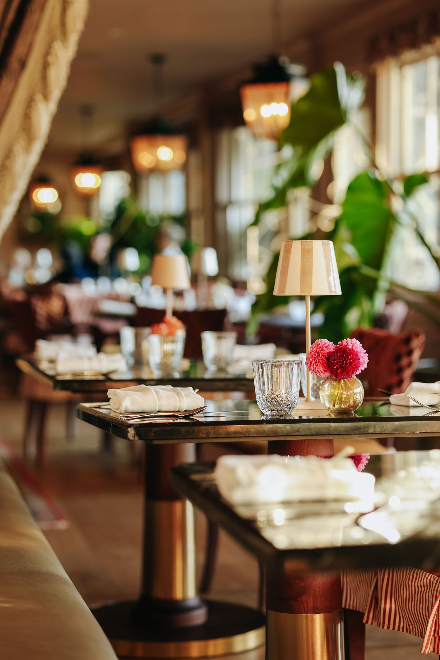 Restaurant interior with elegant place settings, wine glasses, and soft lighting creating an upscale dining atmosphere.
