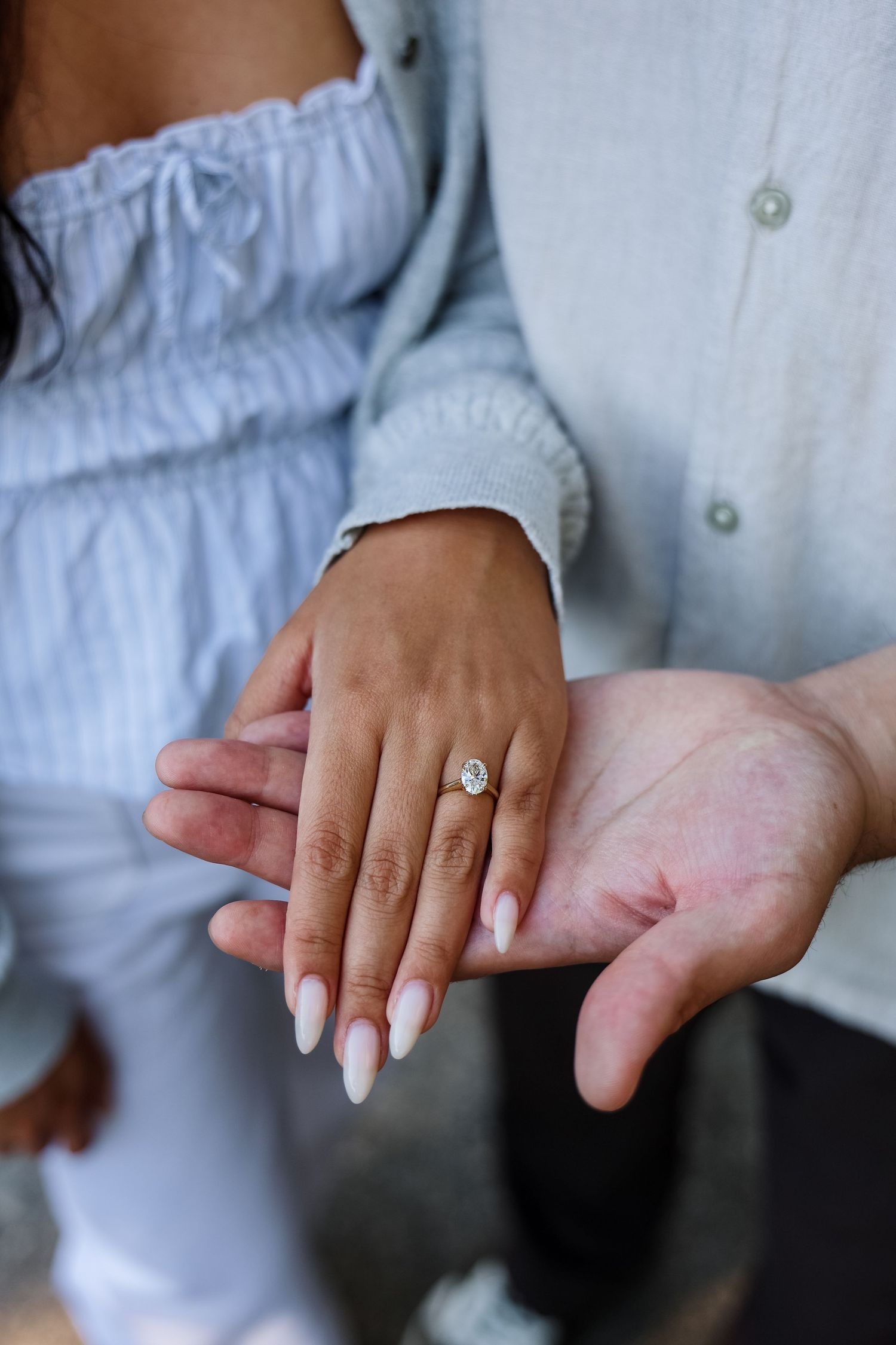 Close-up of an engagement ring on a woman's hand resting on a man's palm, symbolizing a marriage proposal.