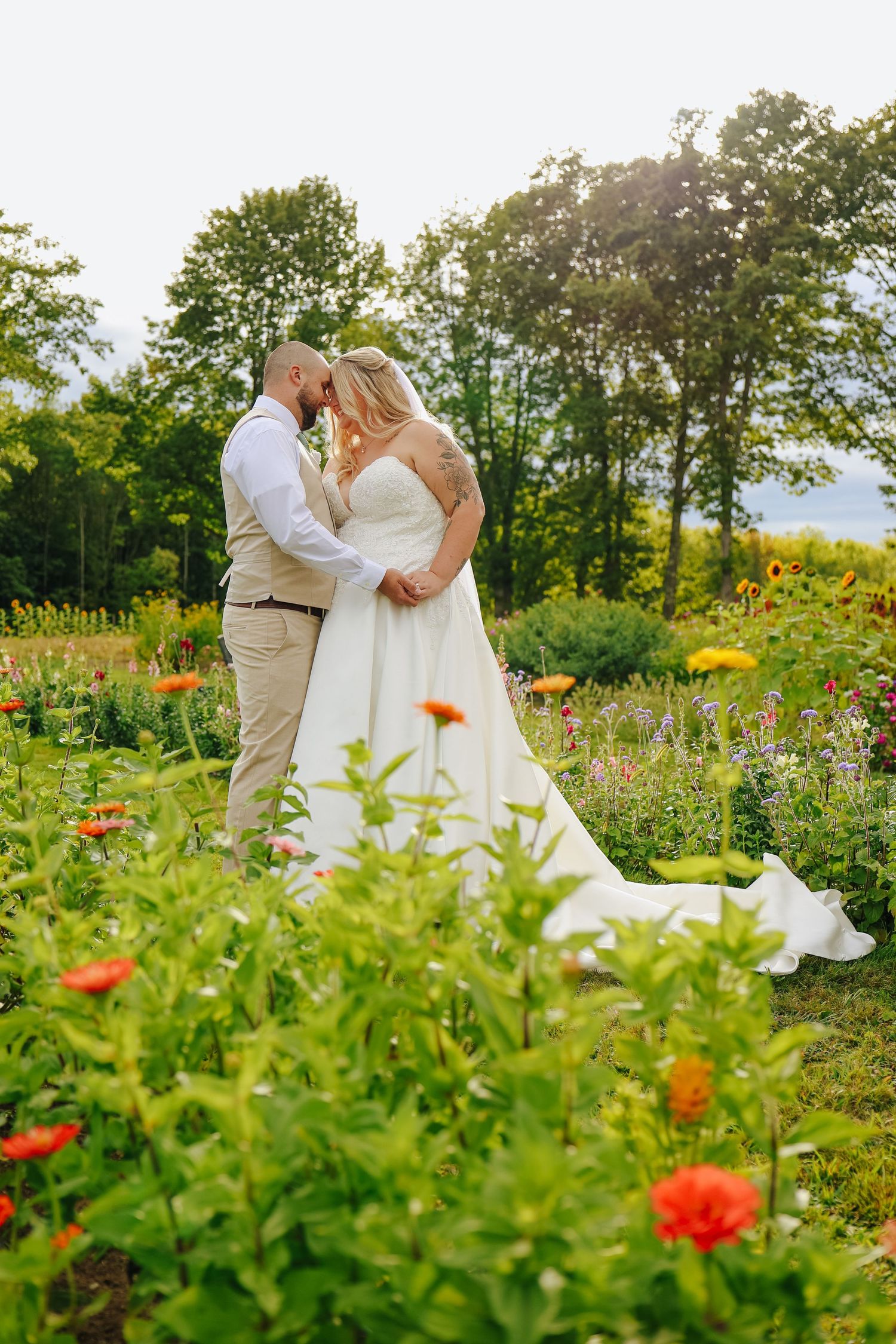 Romantic wedding portrait of bride and groom, captured in a garden filled with blooming orange flowers.