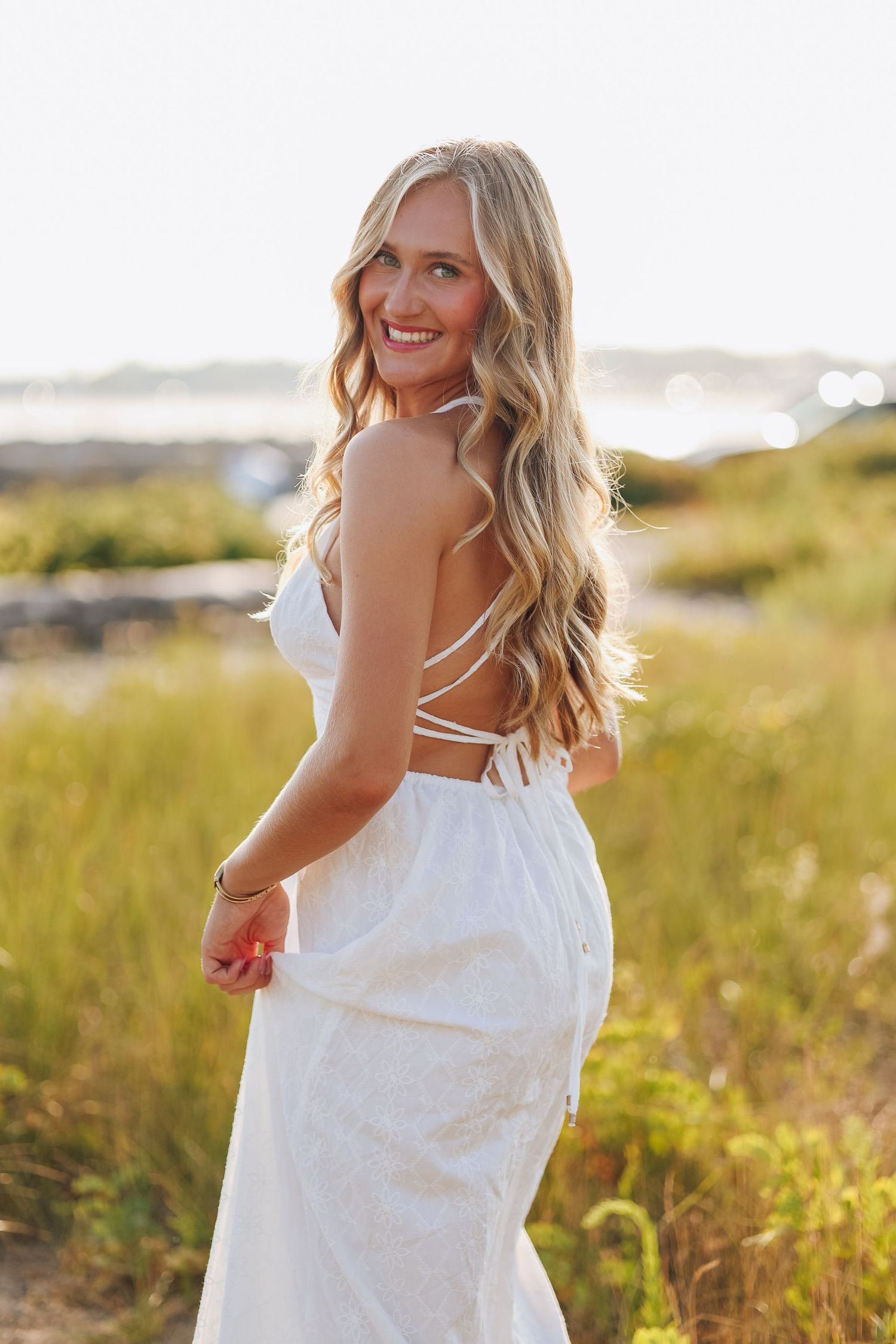 A solo female summer portrait session in a sun-drenched field during golden hour.