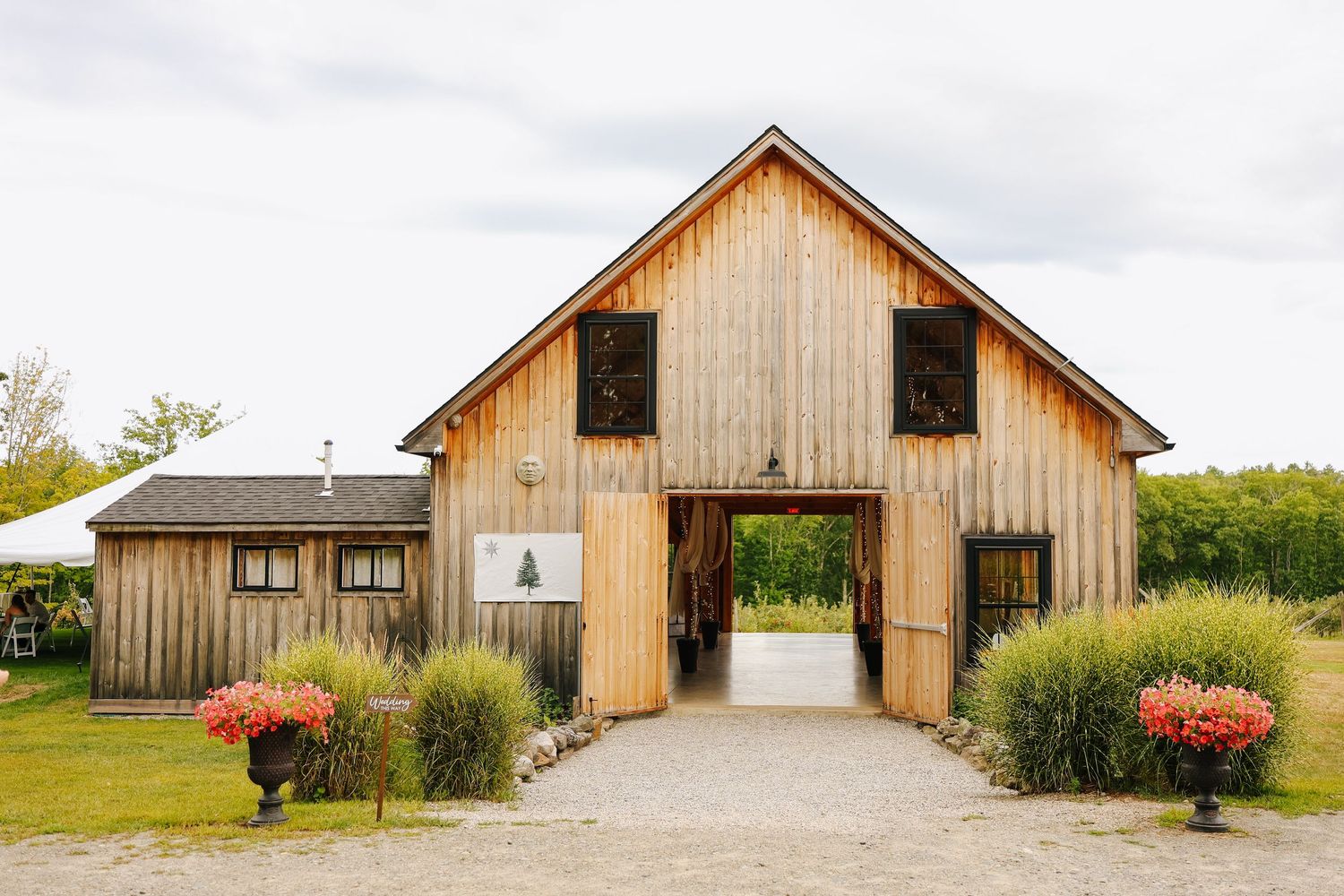 Rustic wooden barn venue with natural wood siding and white trim on a cloudy day.