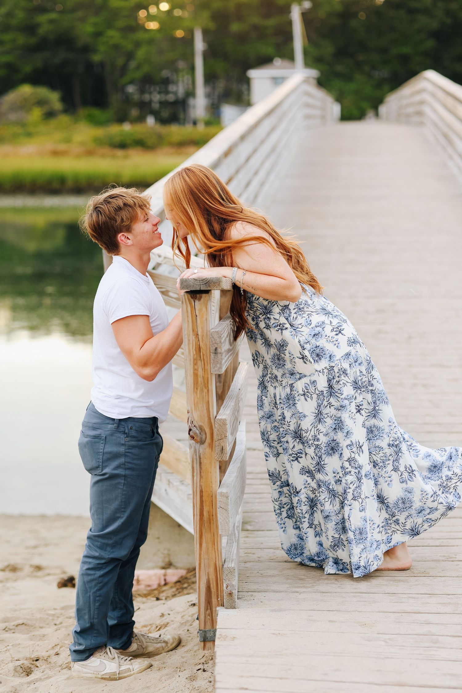 Playful couple sharing romantic moment on wooden boardwalk by waterfront.