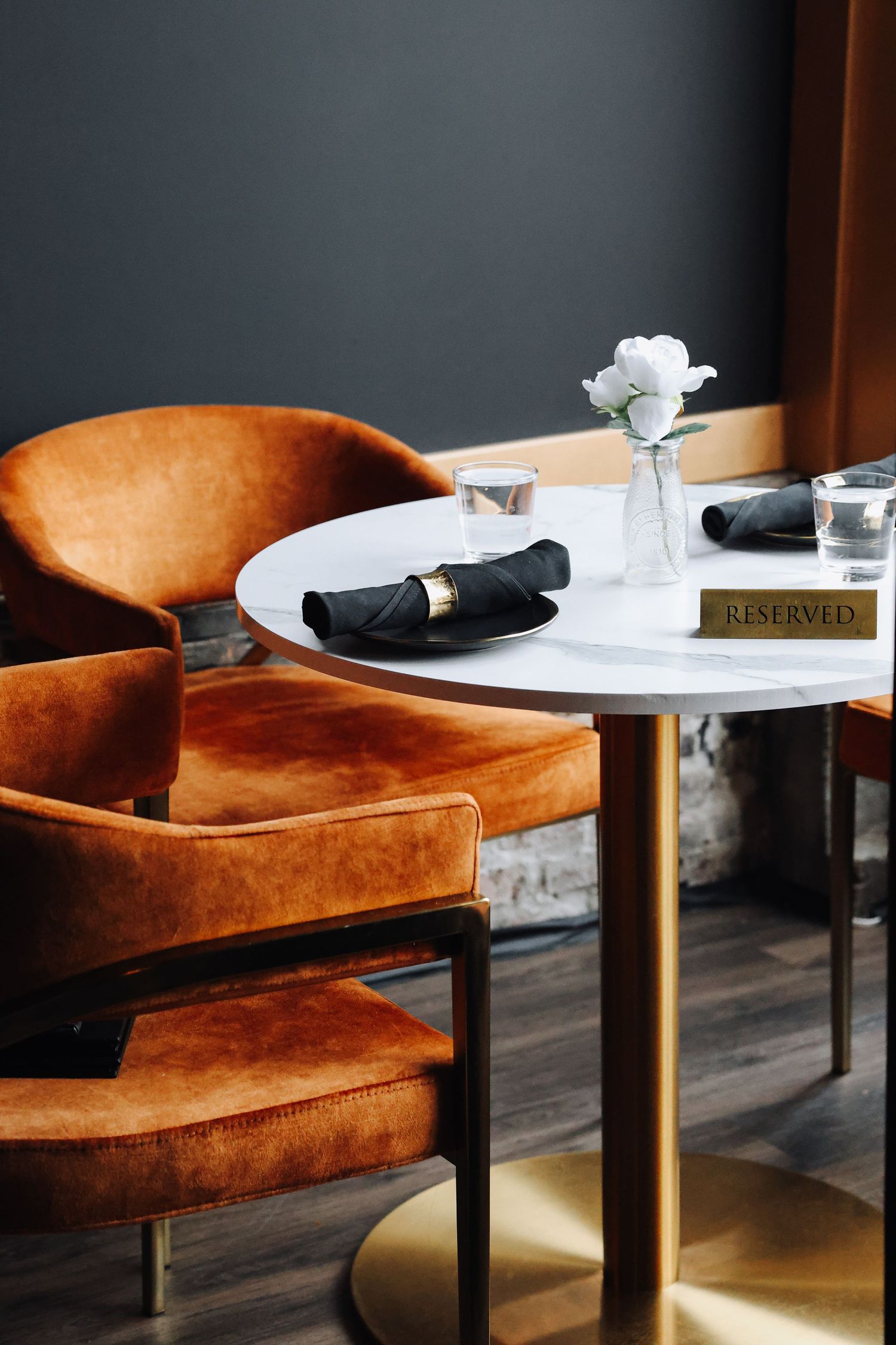 Modern restaurant interior with velvet chairs and white marble table set for dining.