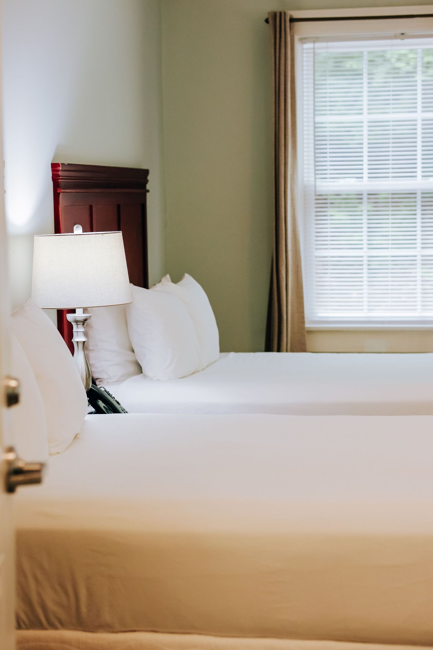 Clean, minimalist hotel room with white bedding and natural light from windows photographed for hotel marketing in Maine