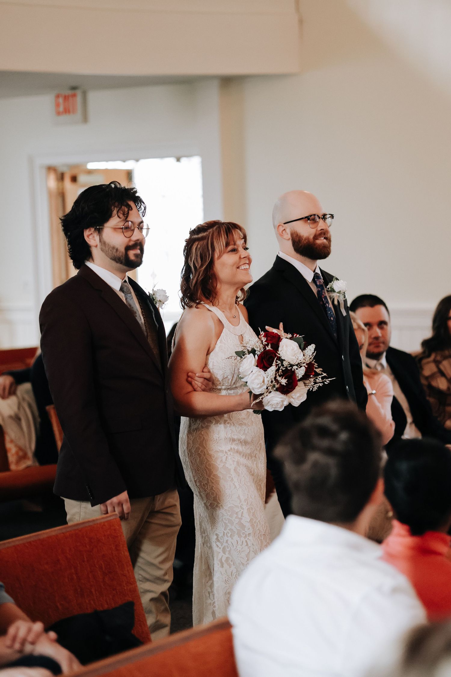 A wedding ceremony unfolds in a bright church interior as guests watch the couple at the altar during their special moment.