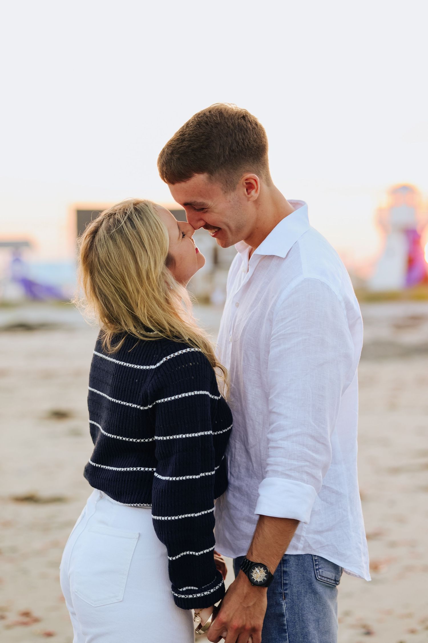 Couple embracing on beach during golden hour sunset.