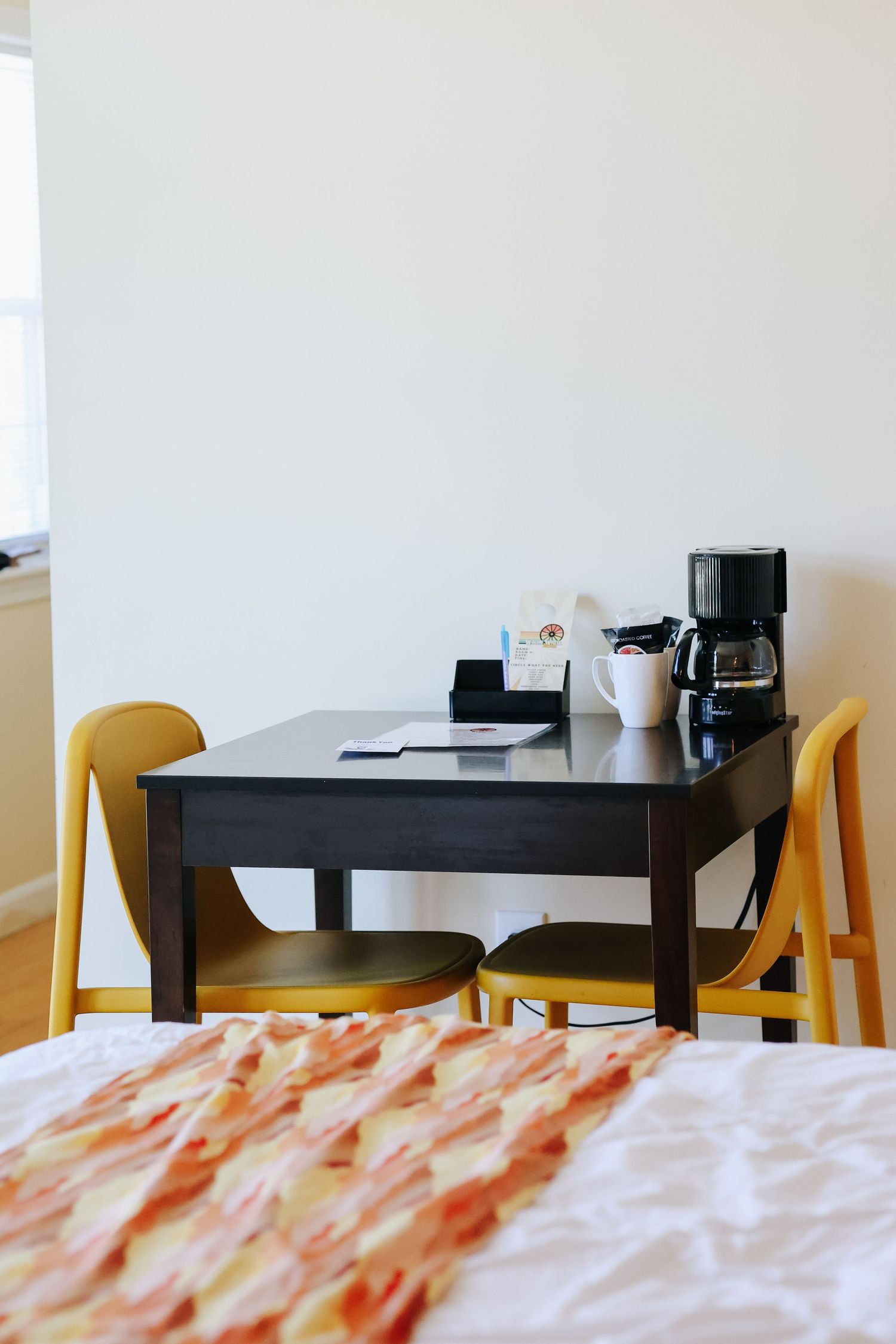 Simple hotel room workspace with black table and orange chairs, photographed for hotel marketing in Maine