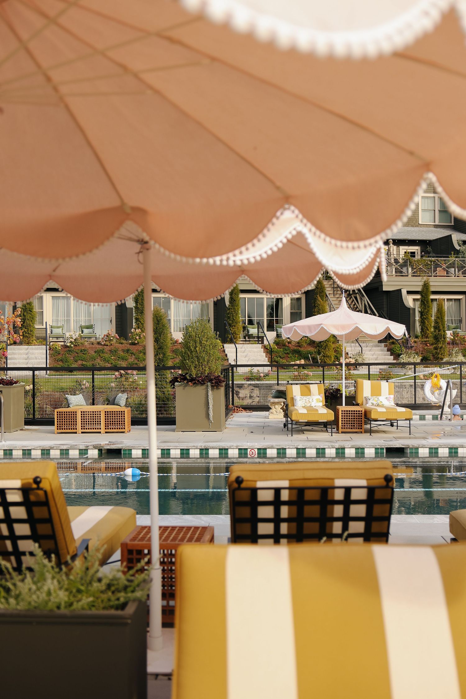 Boutique hotel pool in Maine with yellow lounge chairs and pink umbrellas, hospitality photography highlighting outdoor relaxation space
