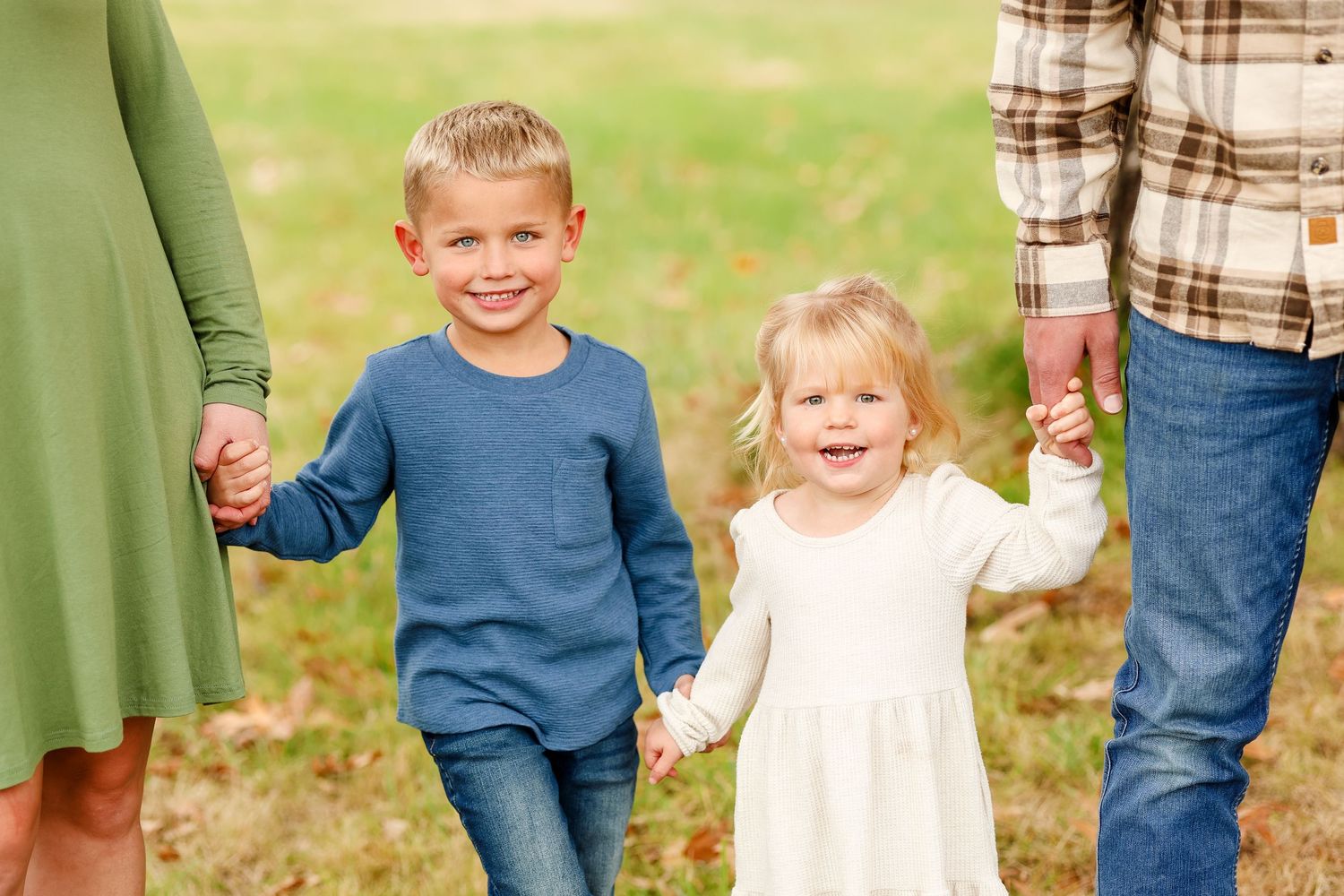 Two children smiling and holding hands, fall family portrait session