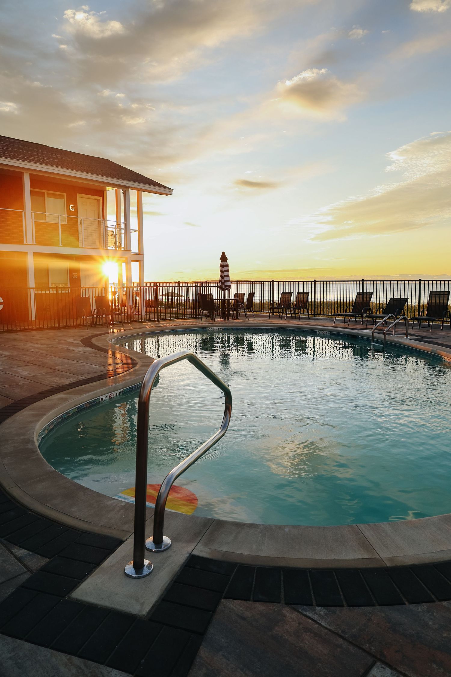 A scenic poolside view at sunset with lounge chairs and ocean views, highlighting beachfront hotel property in Maine