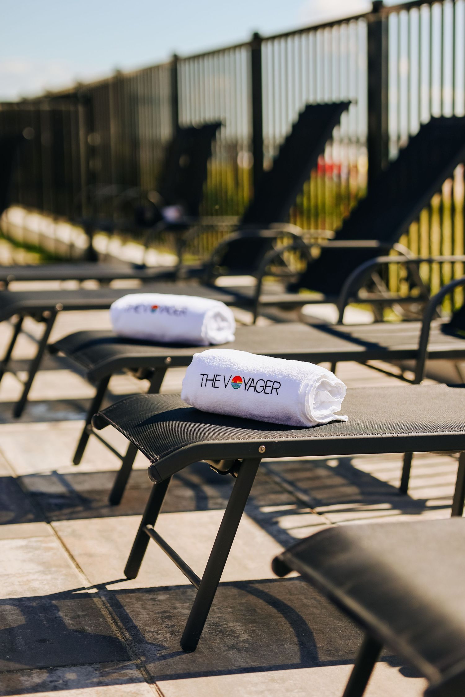 Row of black lounge chairs with white towels on a sunny deck, photographed for hotel marketing in Maine