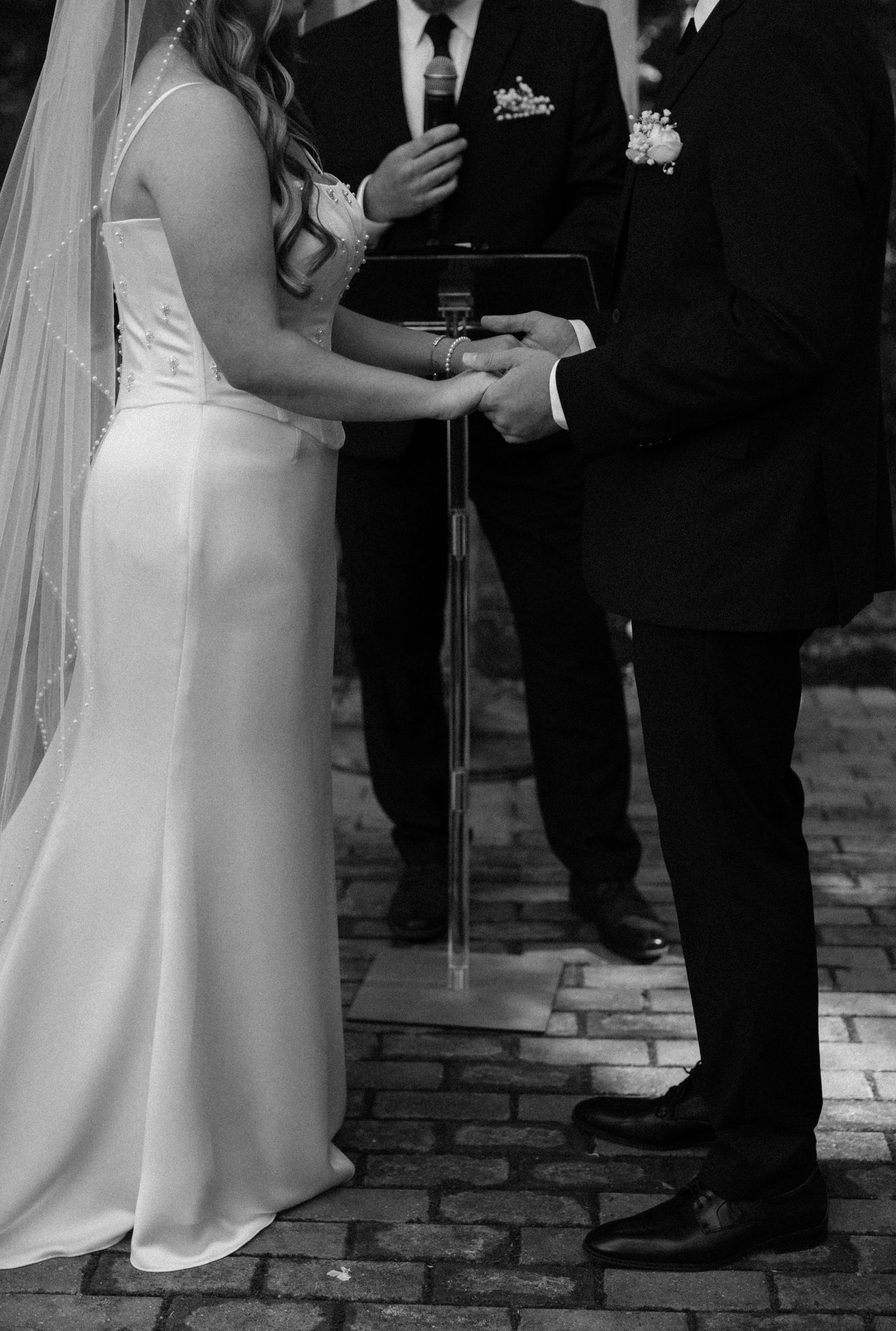 Black and white photo of a wedding ceremony with bride in white dress and groom in dark suit.