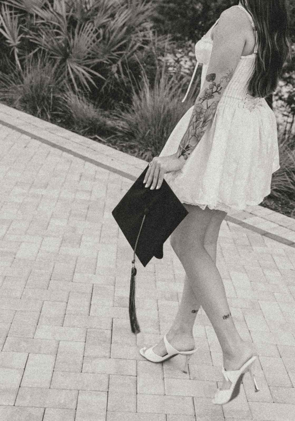 Black and white photo showing white dress and shoes against patterned stone pavement.