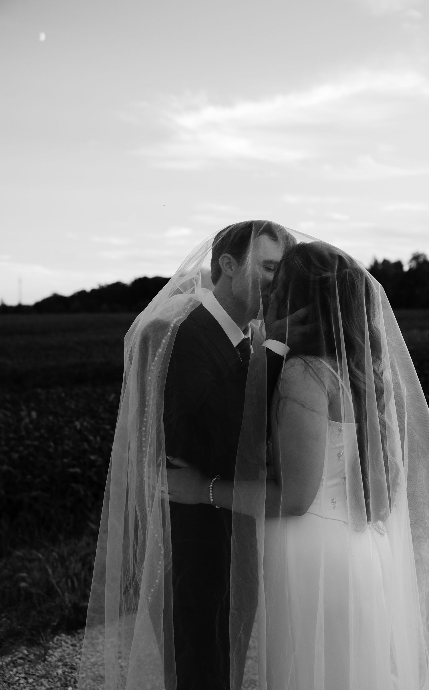 Romantic black and white wedding portrait series showing a couple kissing through a veil.