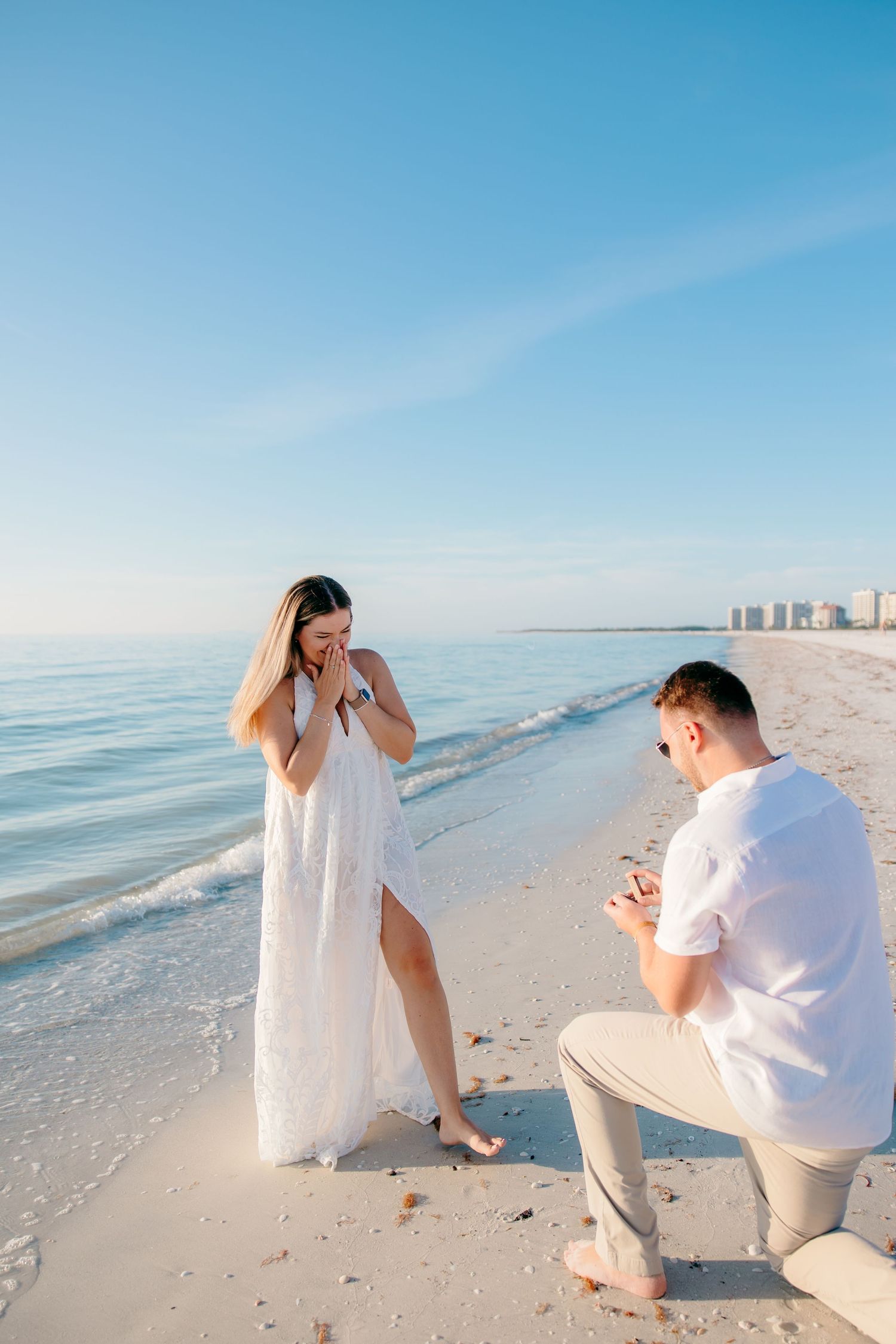 A romantic beach proposal sequence showing a couple on white sand with turquoise ocean and blue sky in the background.