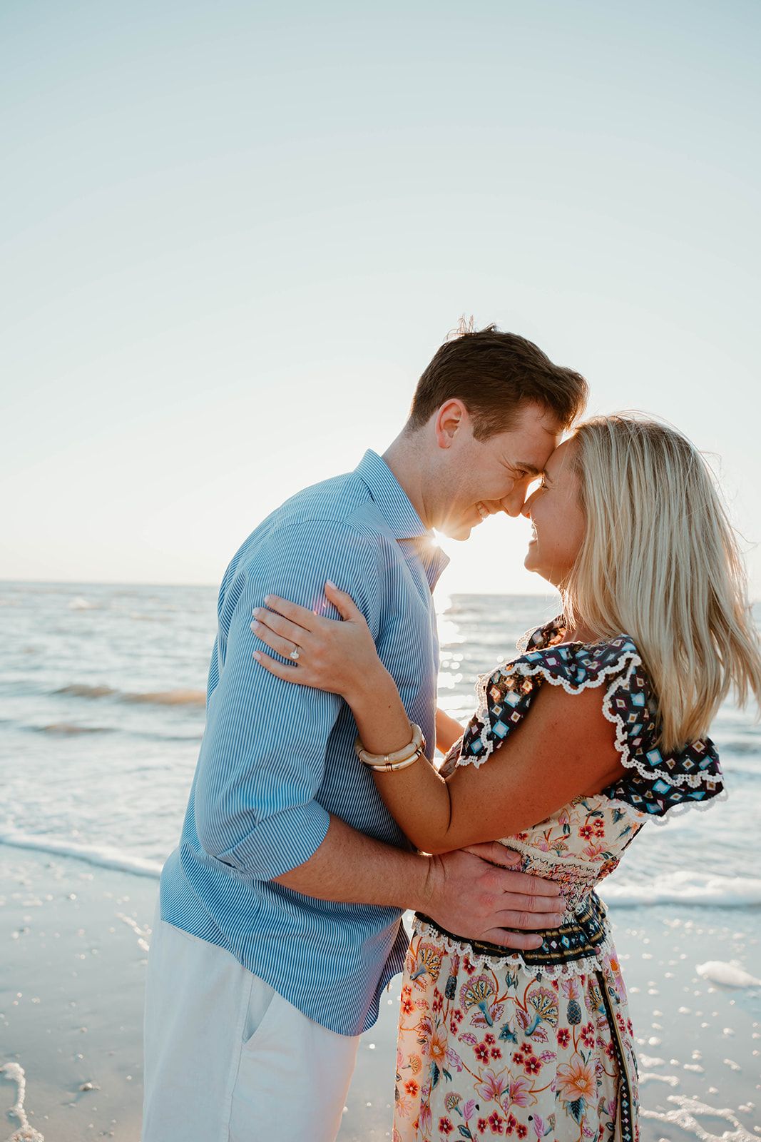 A romantic kiss shared between a couple during their beach engagement photoshoot.
