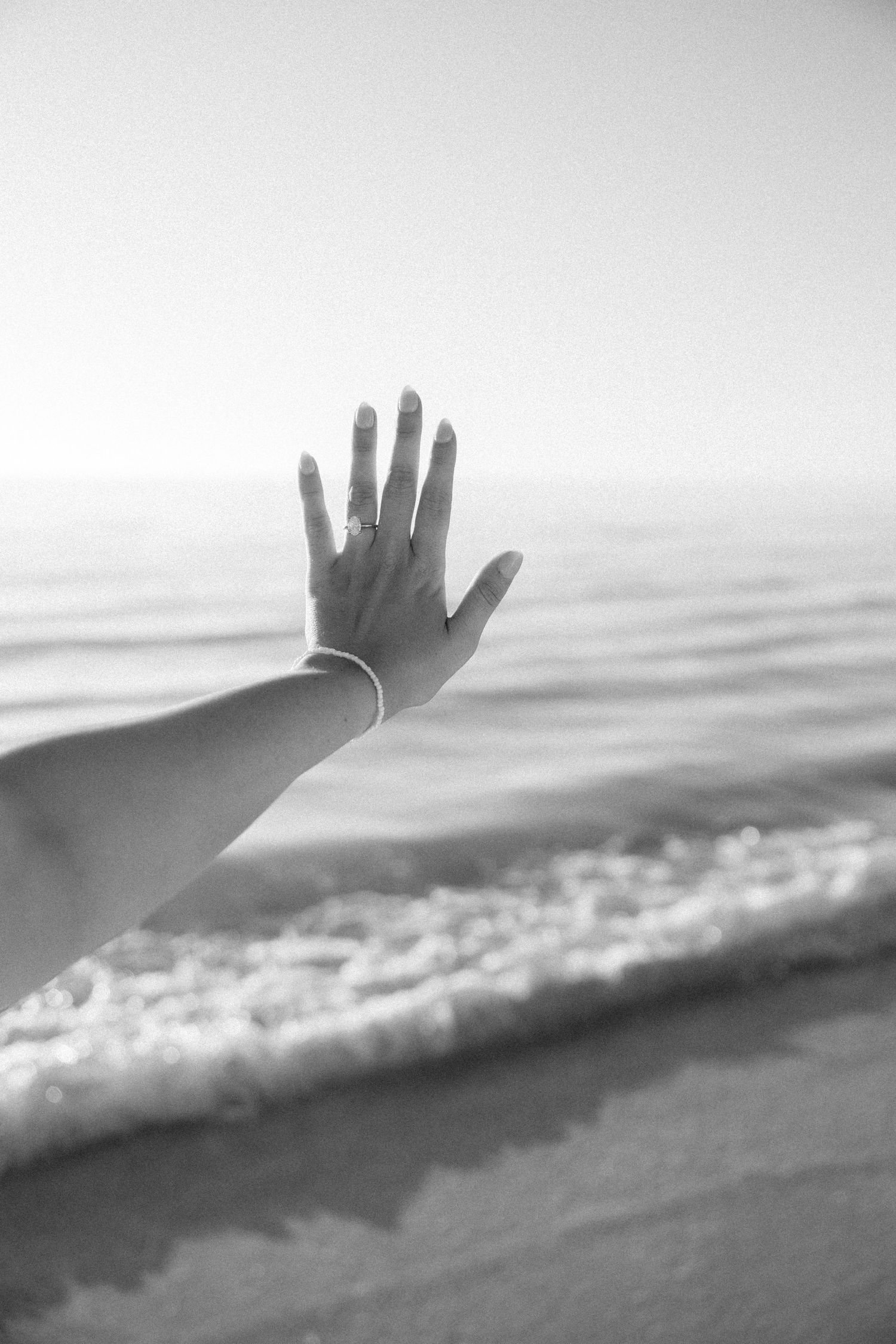 A sequence of black and white photos showing a hand reaching up against a misty ocean horizon.