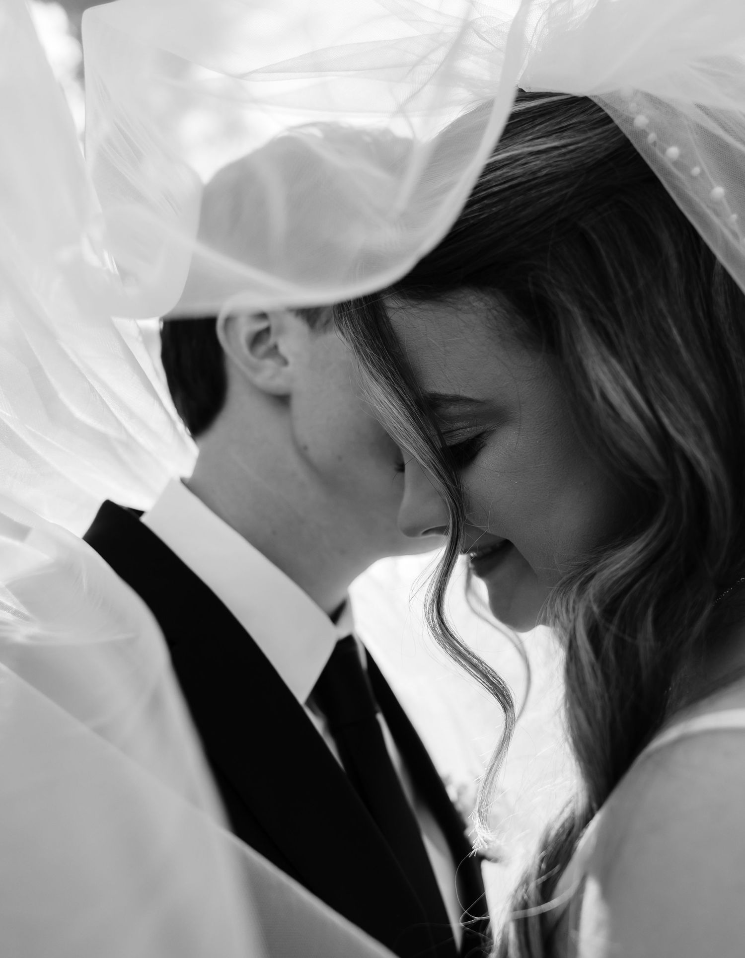 Artistic black and white wedding photo sequence showing intimate moments through a bridal veil.
