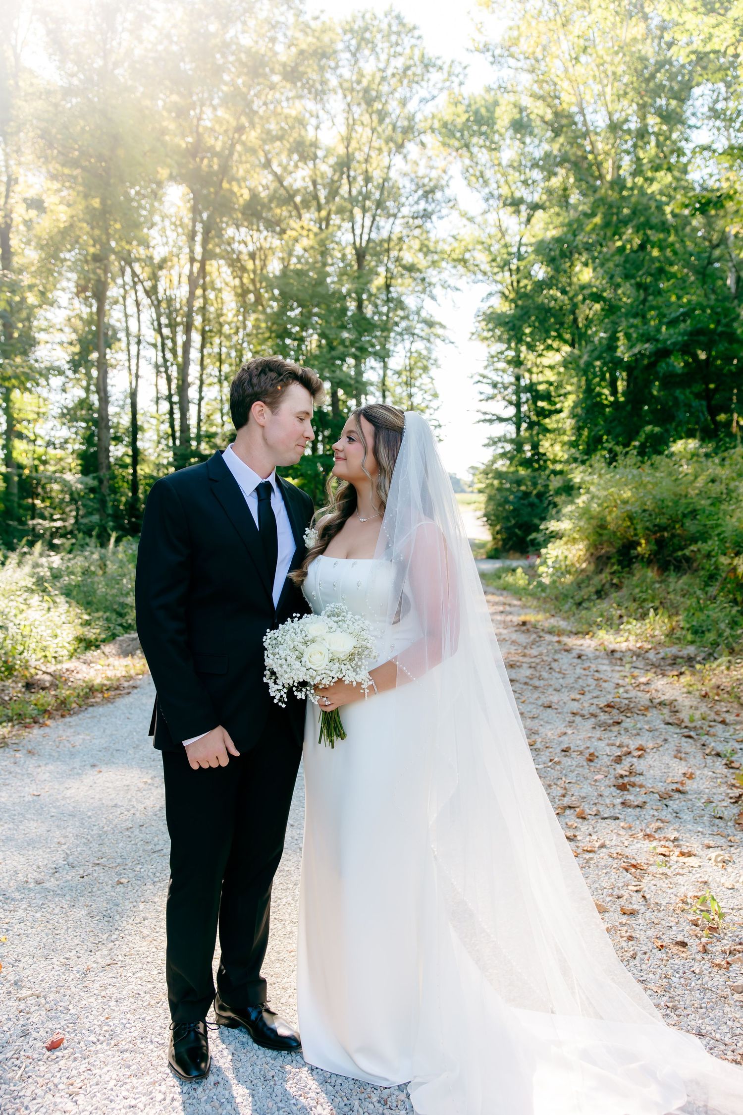 Couple sharing a romantic moment on a sunlit path surrounded by autumn trees.