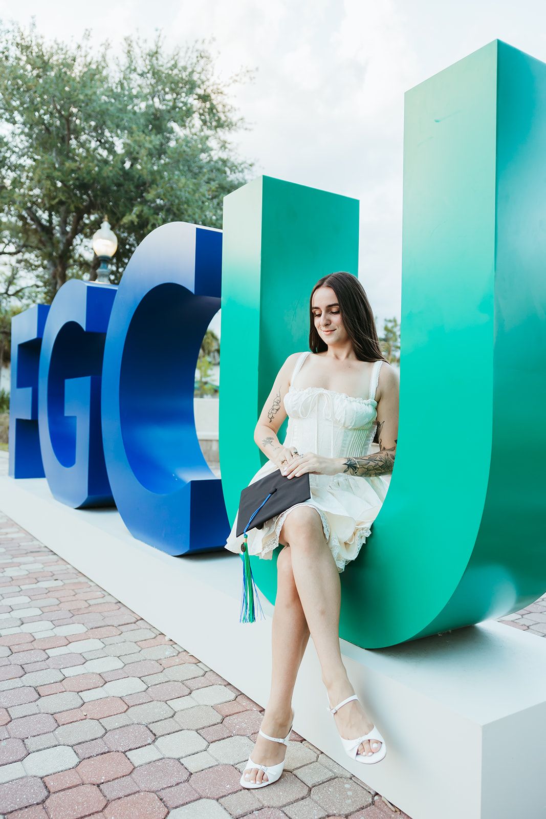 A series of photos showing someone in a white dress posing against large teal and blue letter sculptures outdoors.