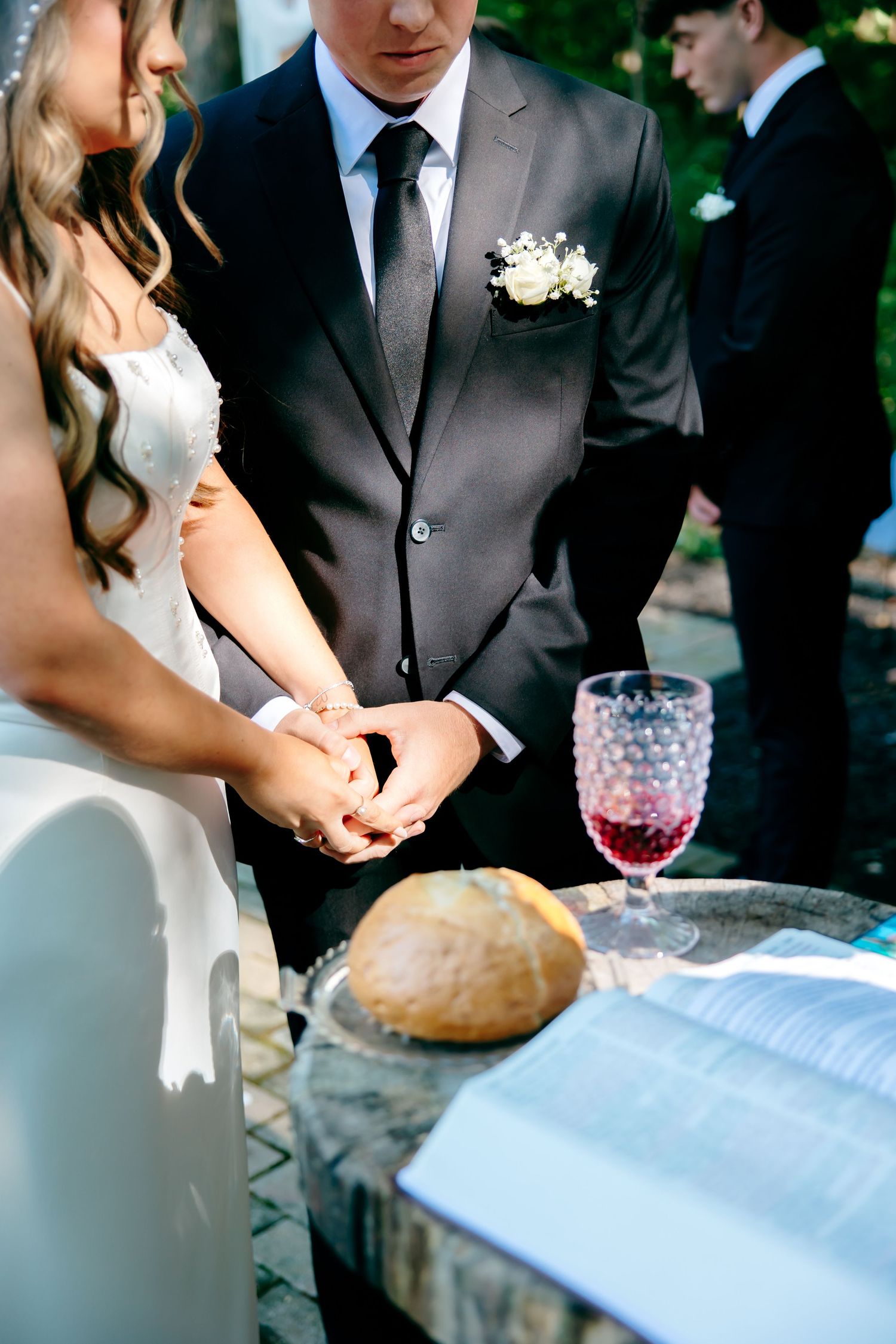 A wedding ceremony moment showing hands and formal attire during a traditional service.