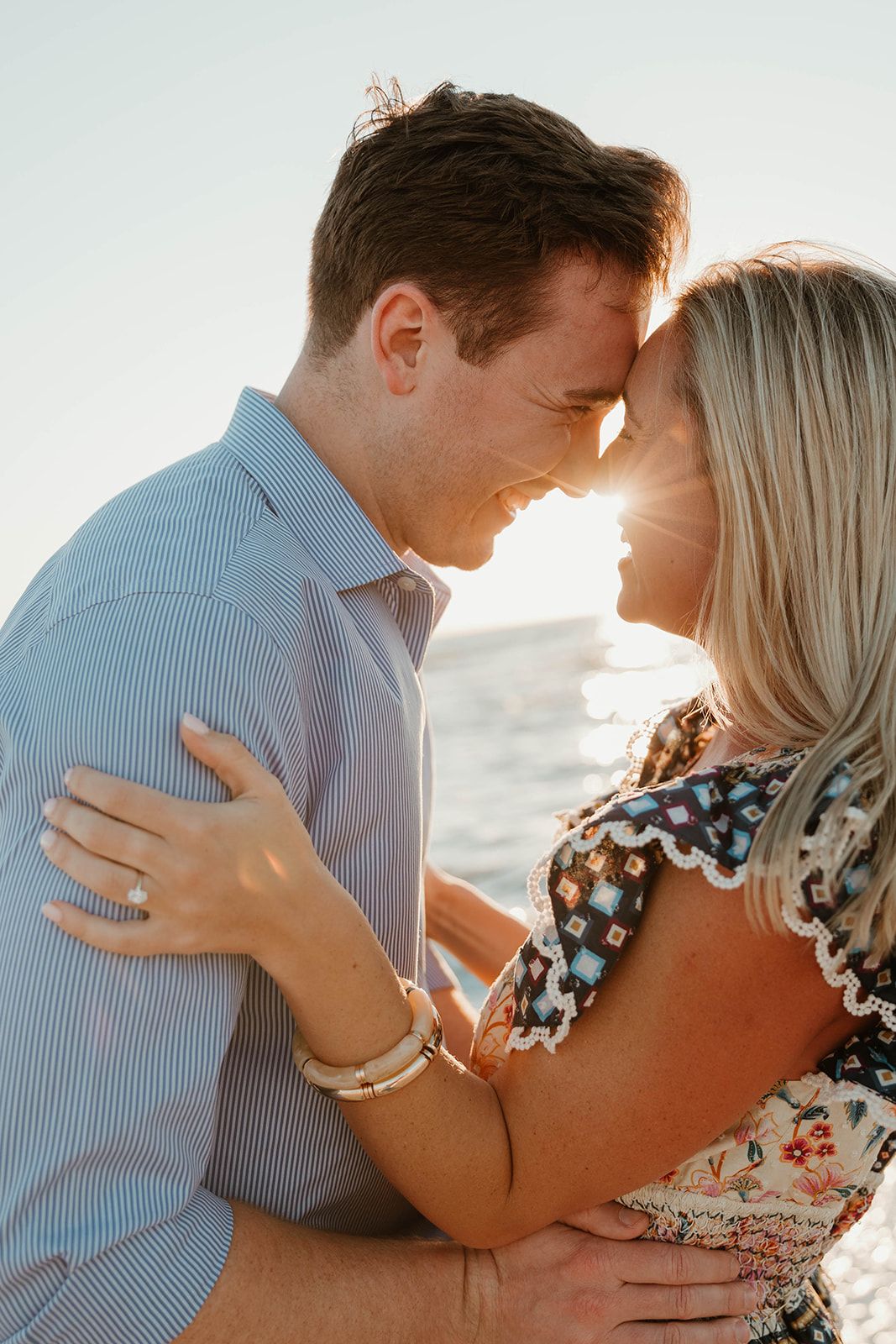 A tender moment between newly engaged couple sharing an embrace on the beach.