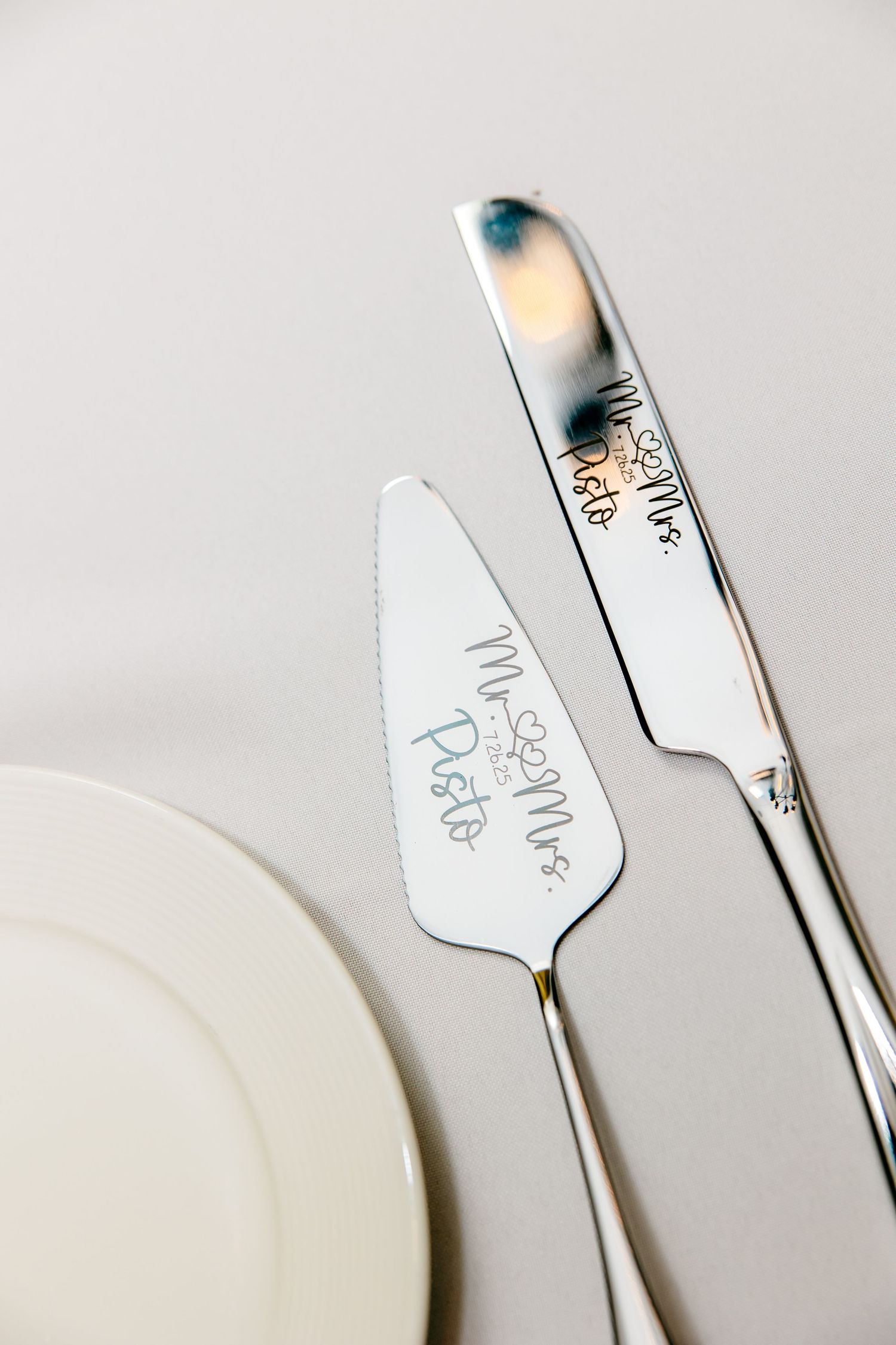 Close-up view of white plates and silverware arranged in a minimalist style on a light gray surface.