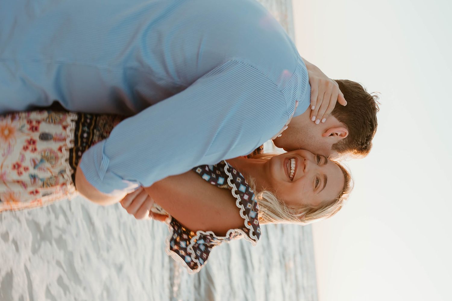 A passionate embrace captured during a beach engagement photo session.