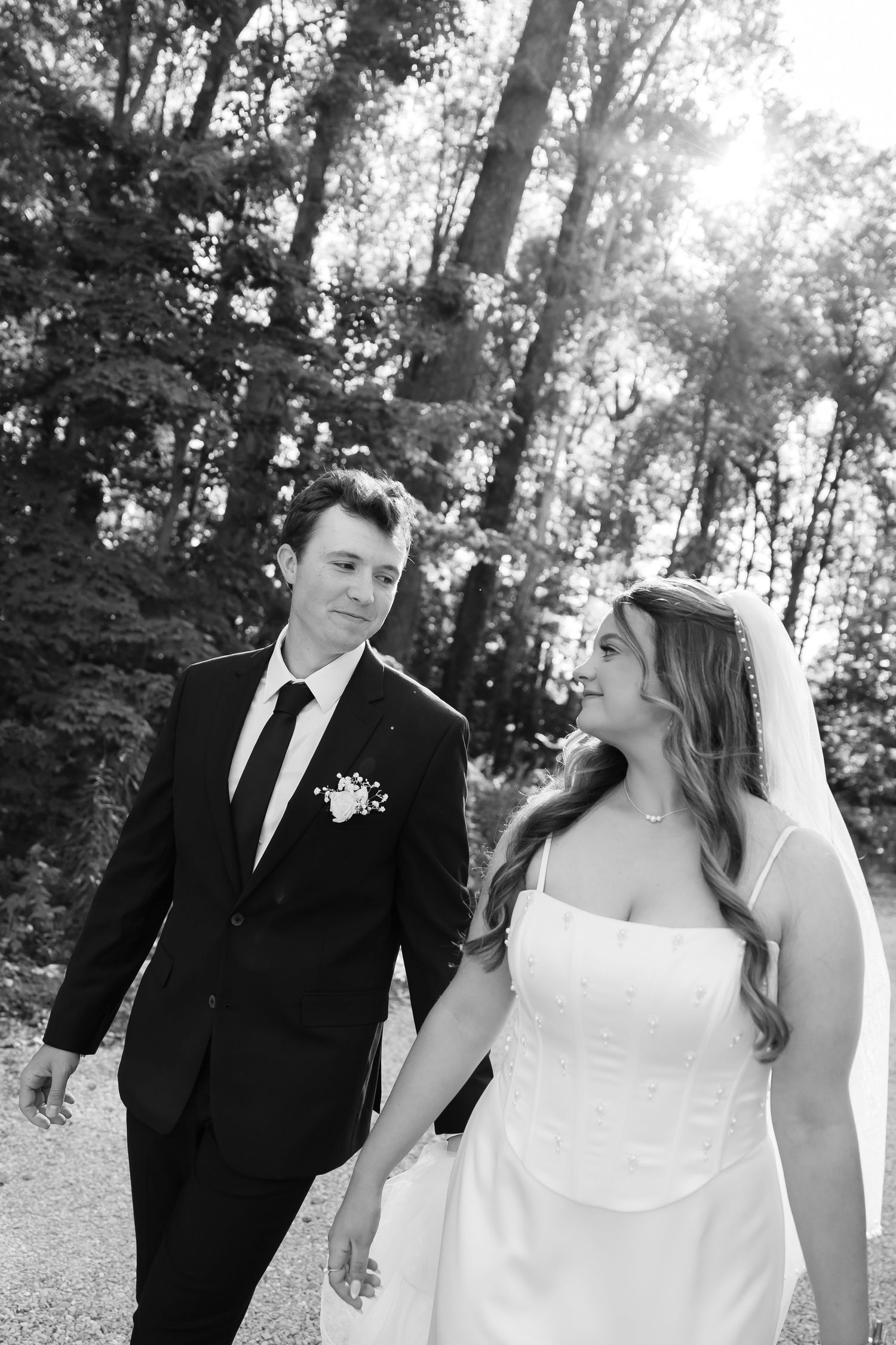 Wedding couple walking and laughing together on a wooded path.