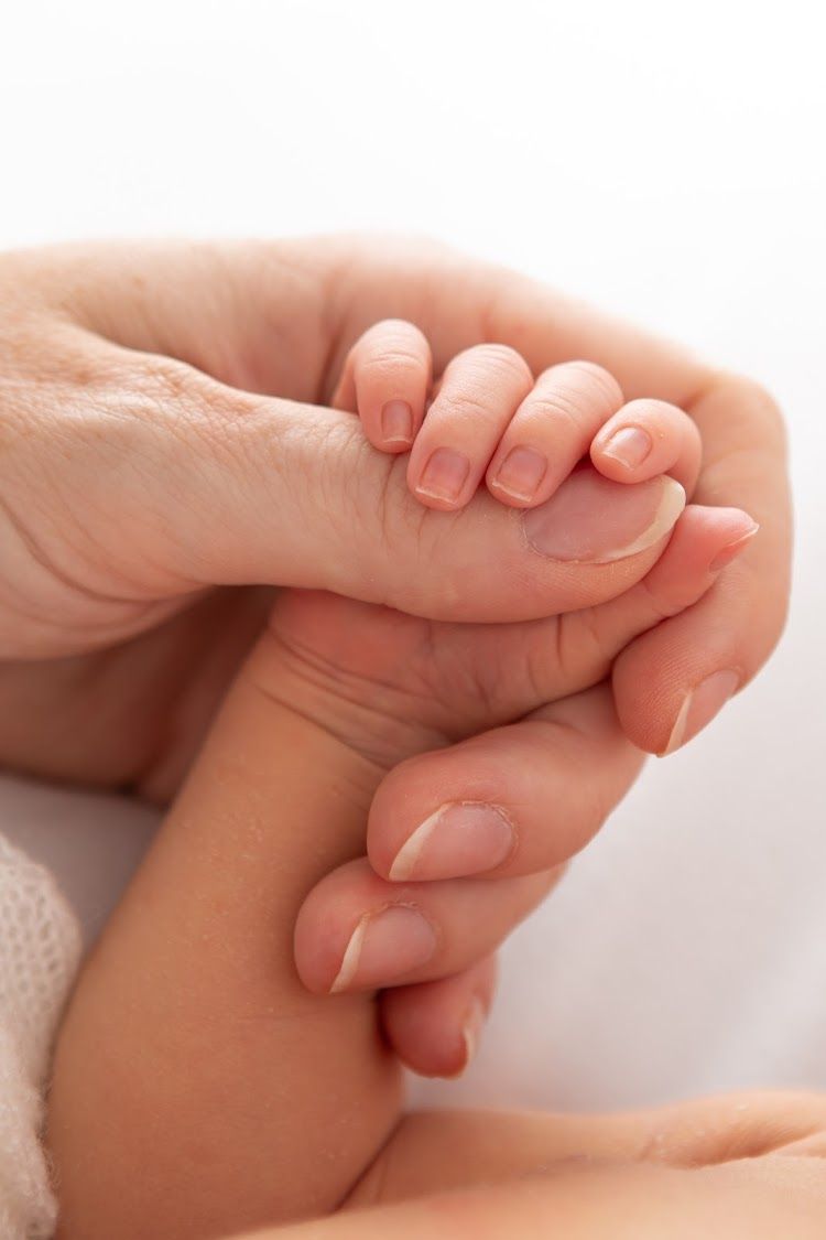 Close-up view of tiny baby toes and fingers against soft white fabric.