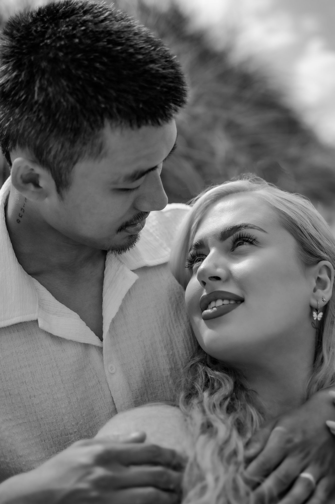 Black and white close-up of a couple gazing at each other tenderly outdoors.