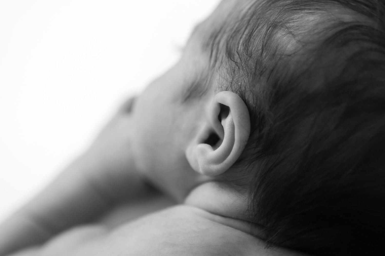 Close-up black and white profile of sleeping newborn showing gentle facial features.