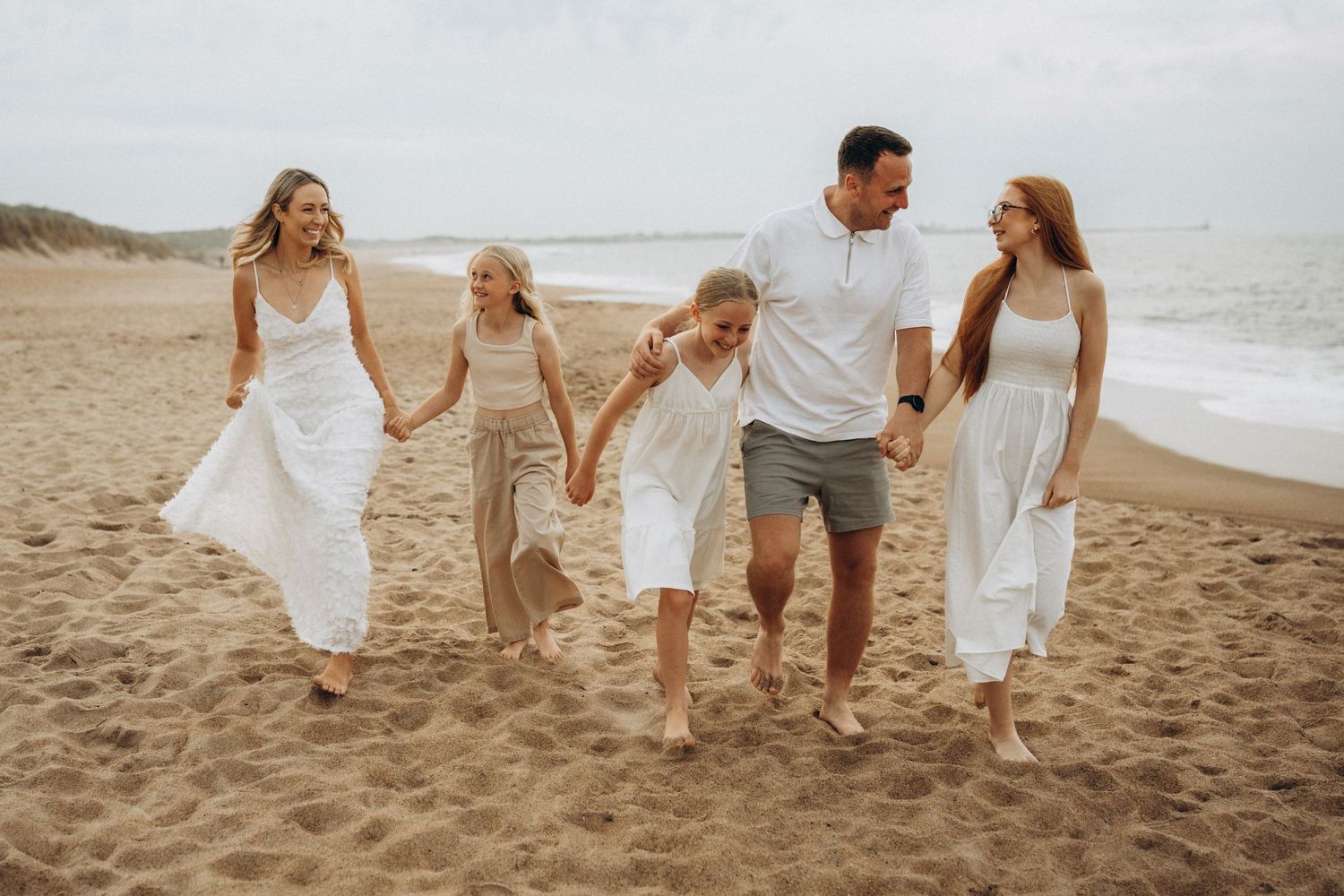 Family walking together along sandy beach shoreline at sunset.