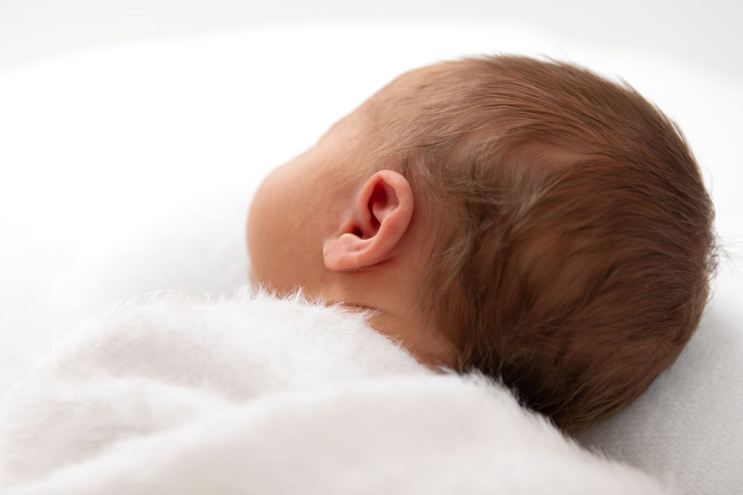 Profile view series of baby resting on white blanket.