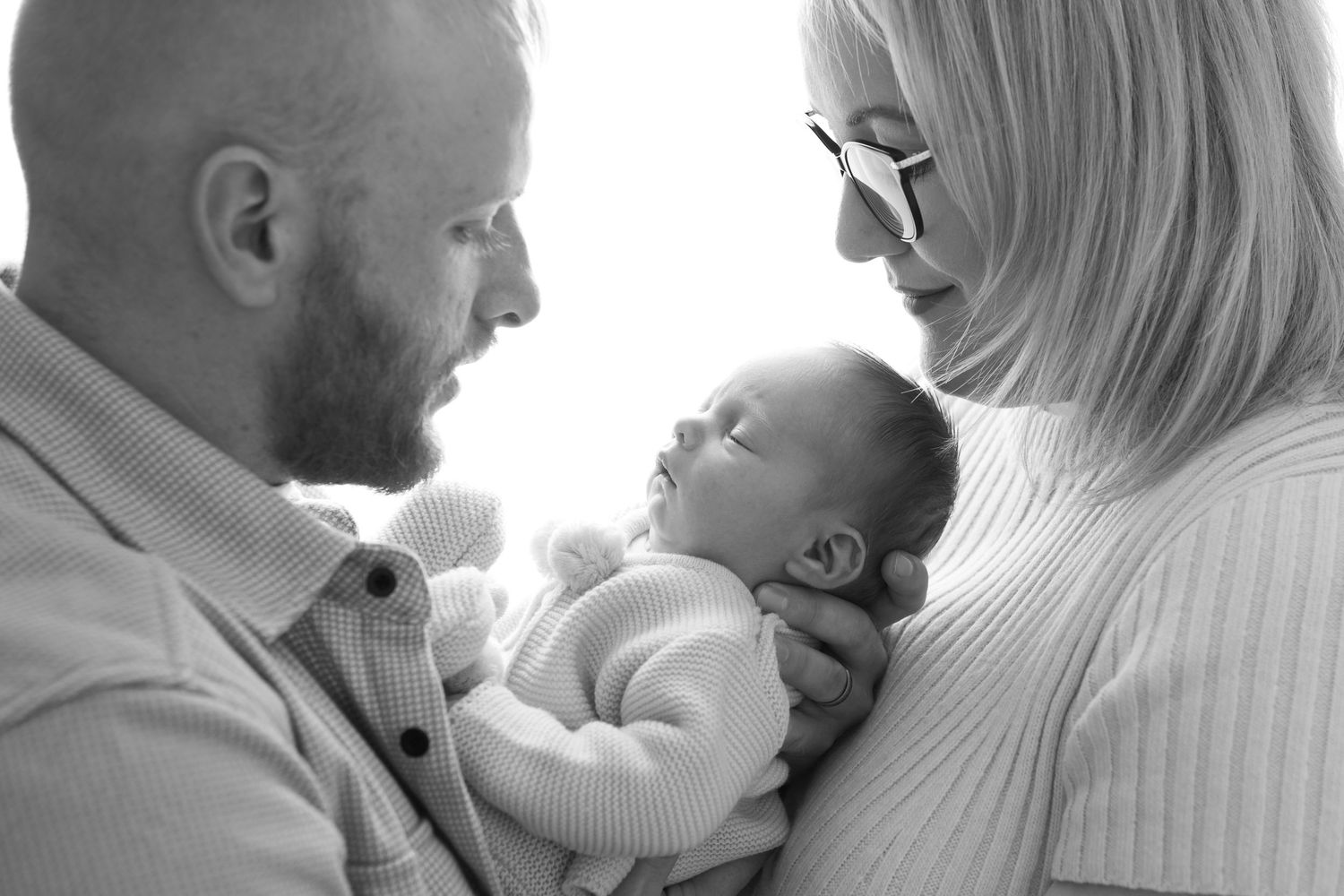 Tender black and white photo series showing parent bonding with newborn baby.