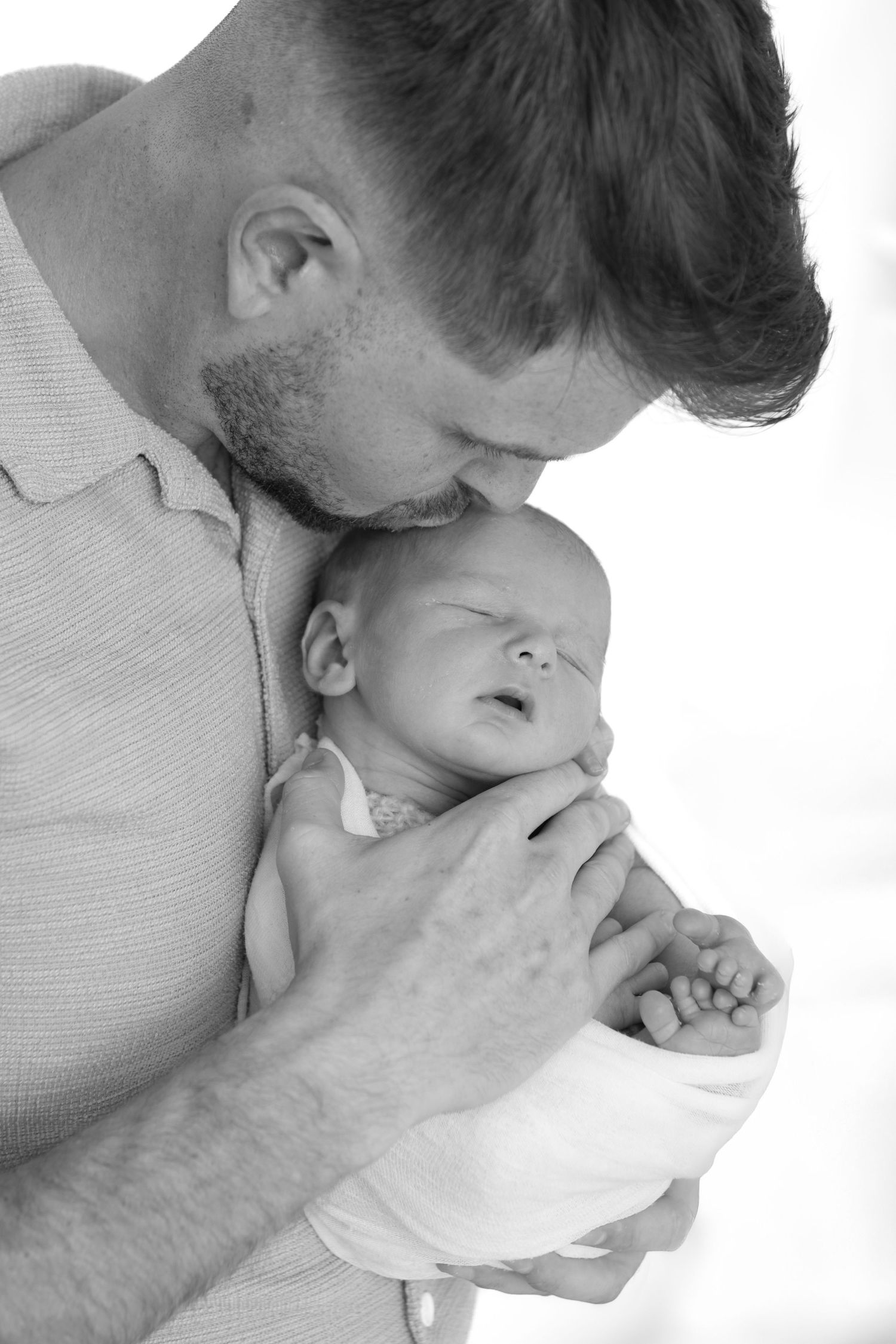 Tender black and white portrait of parent holding sleeping newborn.