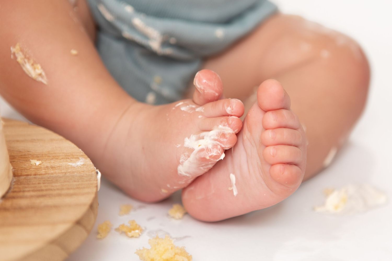 Close-up of a baby's feet covered in cake frosting during a first birthday cake smash celebration.