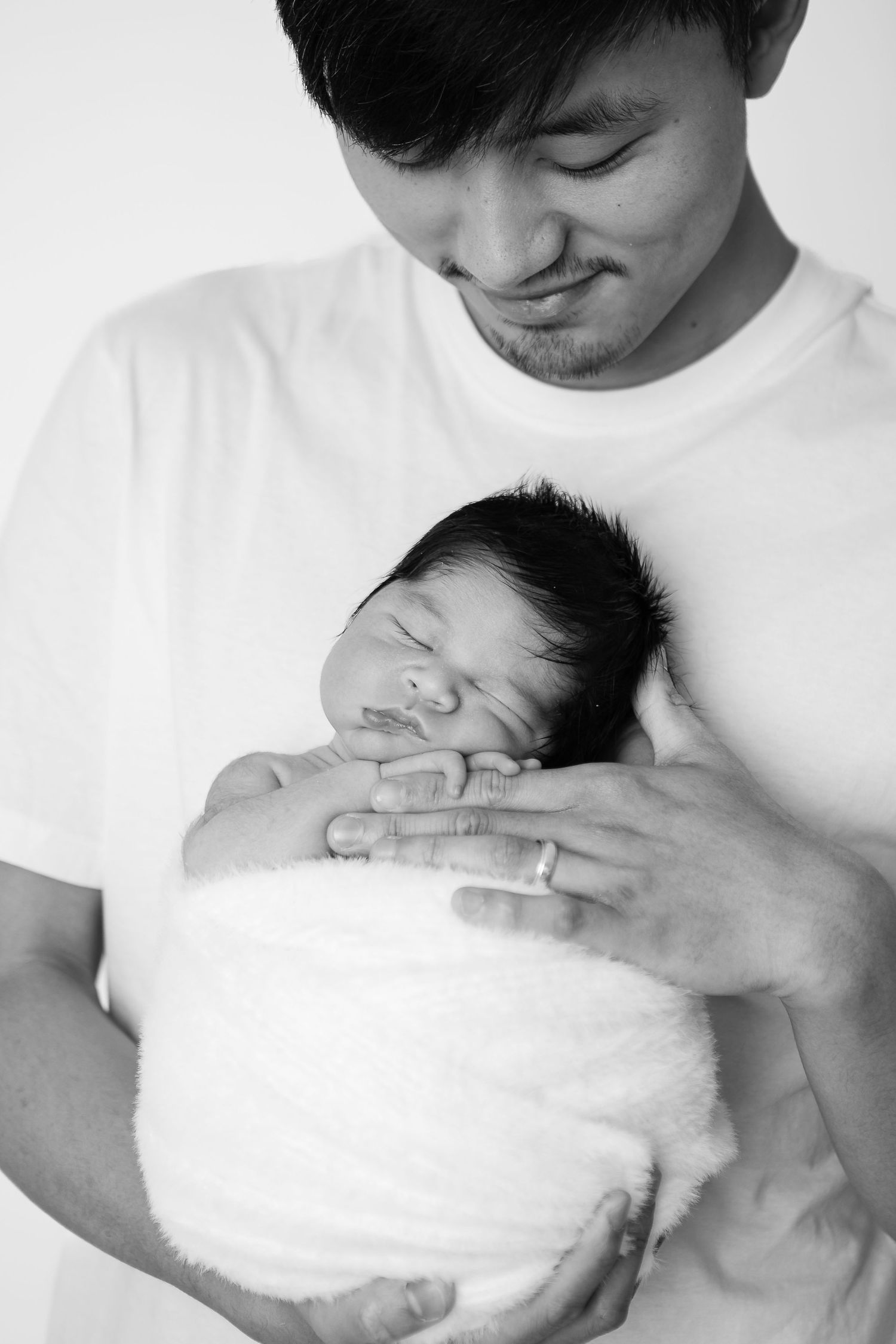Black and white series showing tender moments with a newborn wrapped in white.