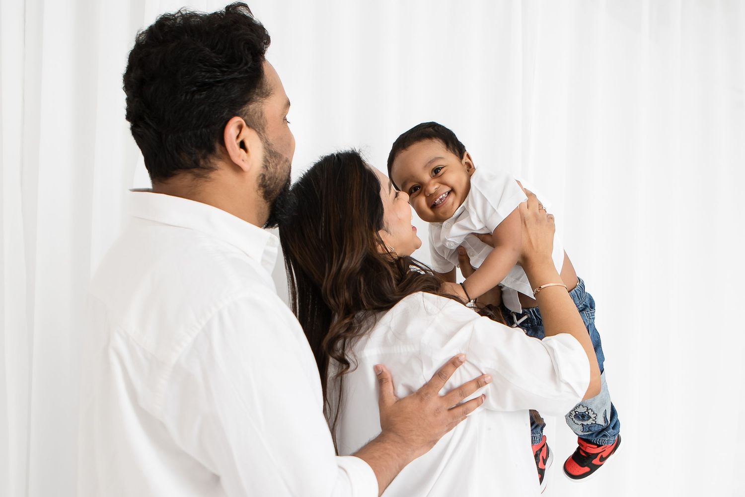 Candid family moments captured against white backdrop in studio setting.