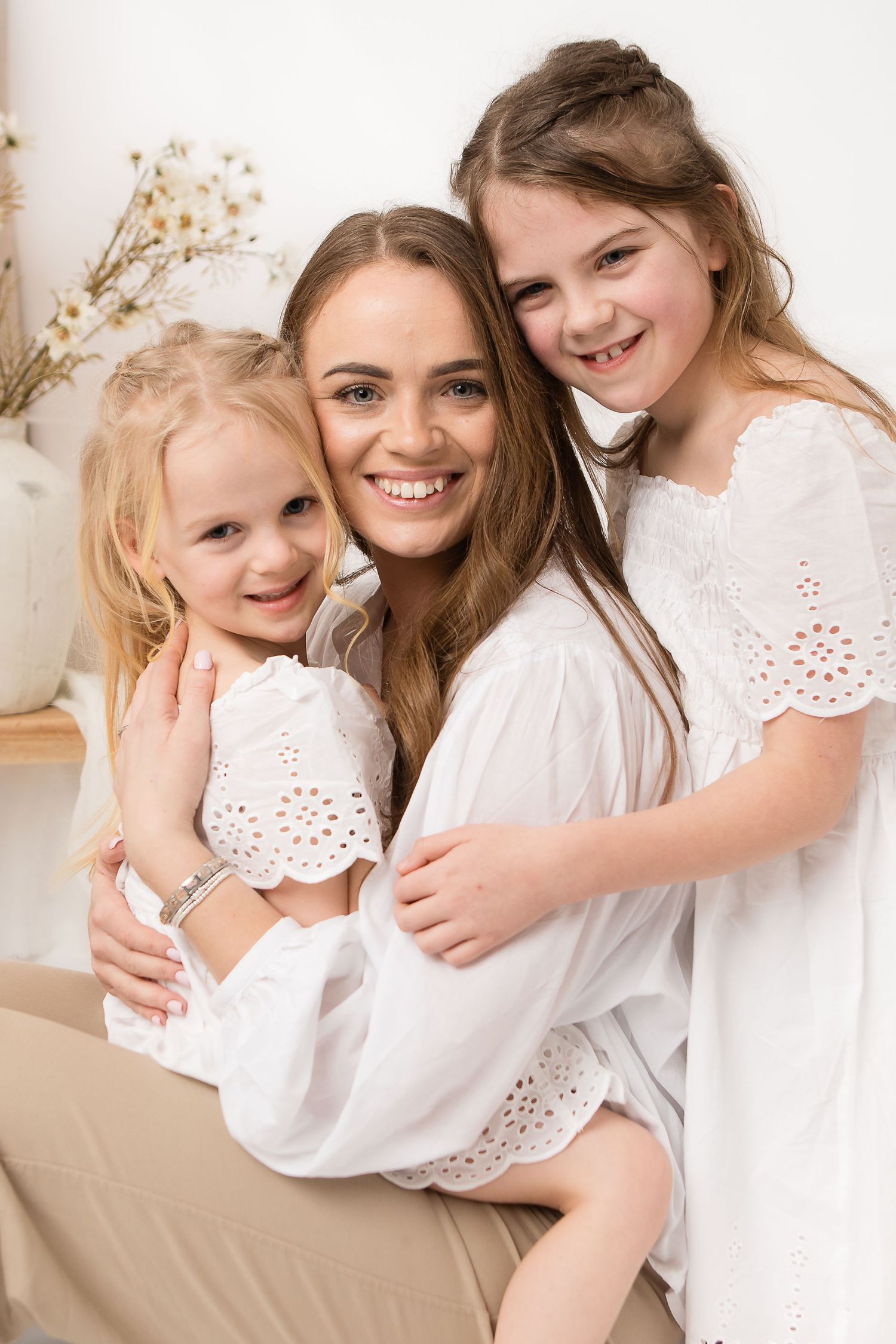 Sweet family portraits in white eyelet clothing against neutral backdrop.