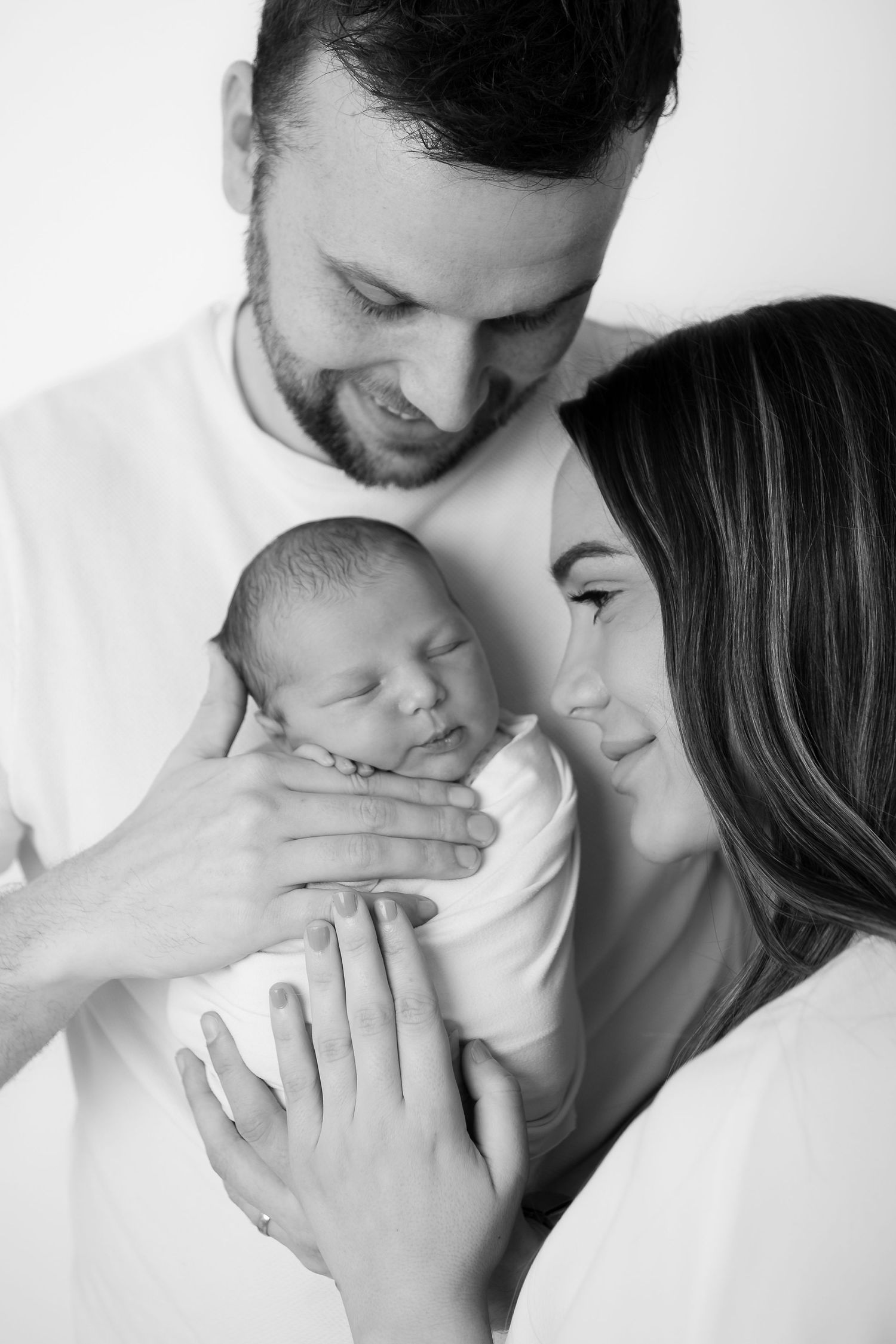 Black and white portrait series of parents tenderly holding their newborn baby.