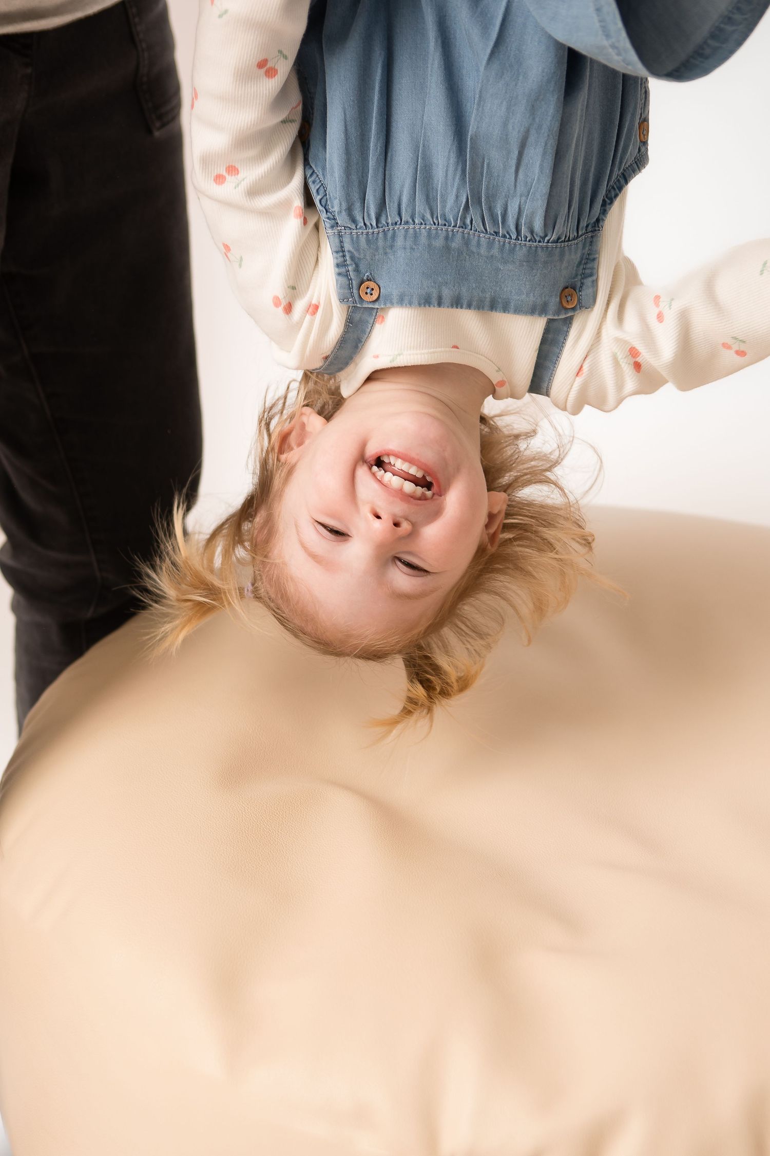 Laughing young girl being held upside down playfully with her blonde hair falling down.