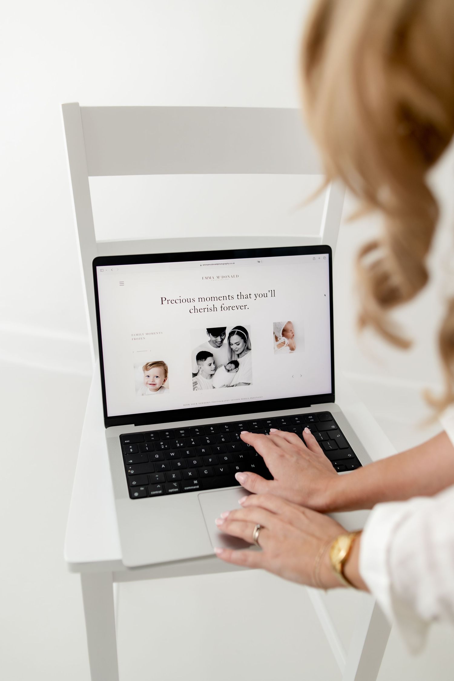Woman typing on laptop displaying a photography website with text Precious moments that you'll cherish forever.