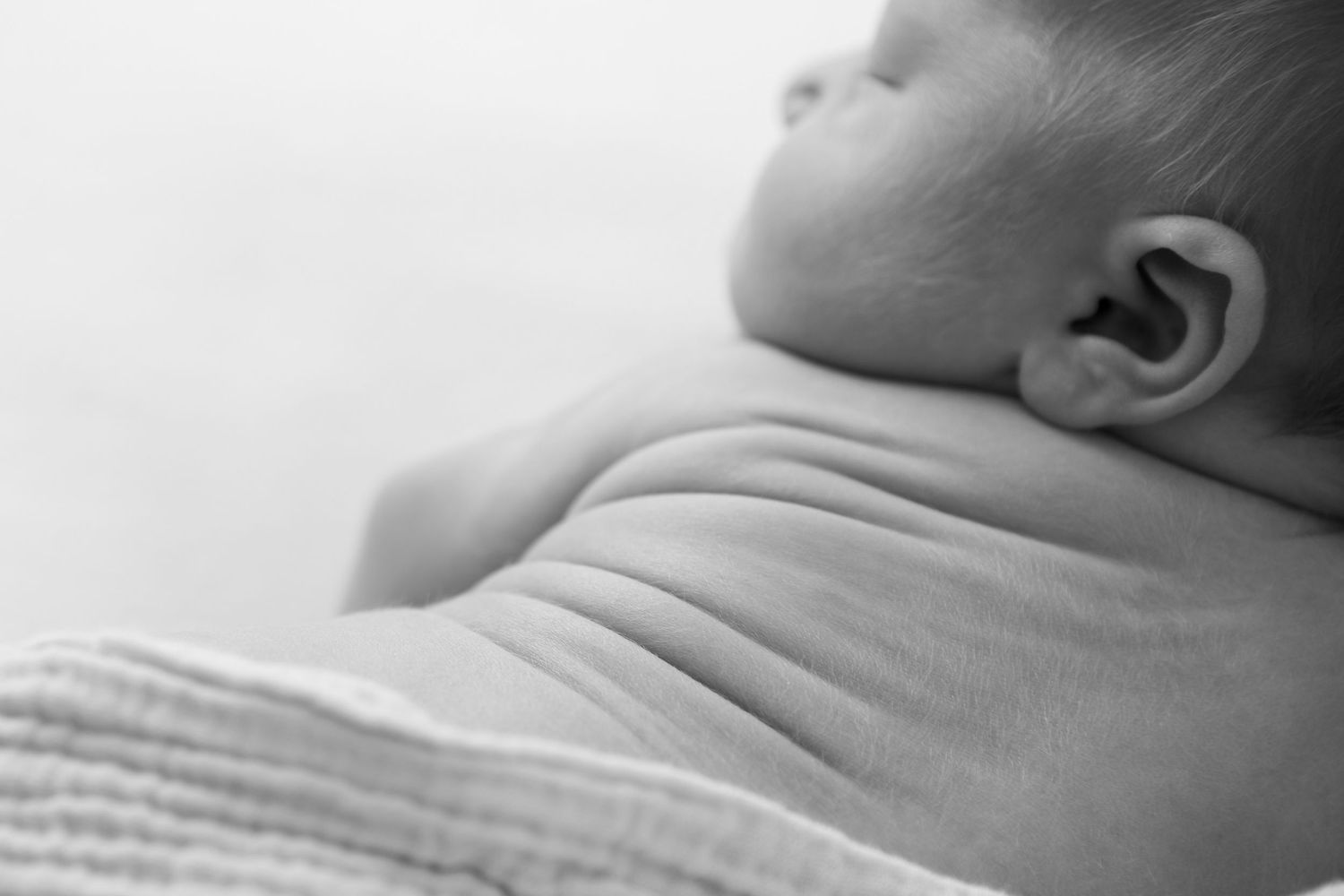 Peaceful black and white profile of sleeping newborn against soft background.