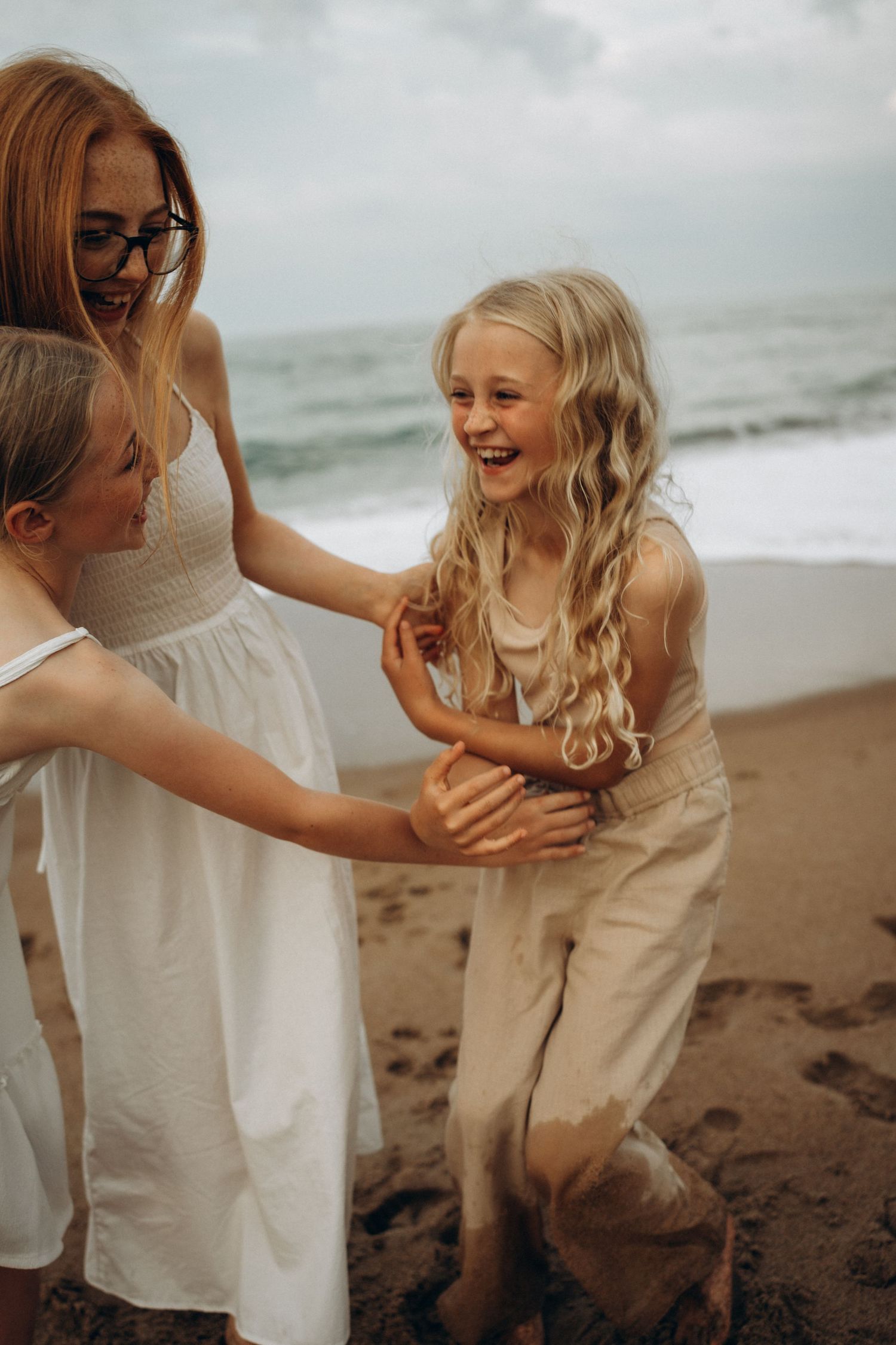 Joyful moments captured on beach with family in white clothing.