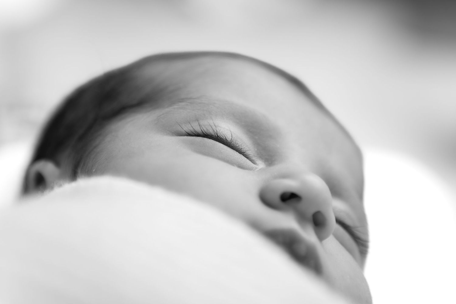 Peaceful black and white portrait of sleeping newborn with soft focus.
