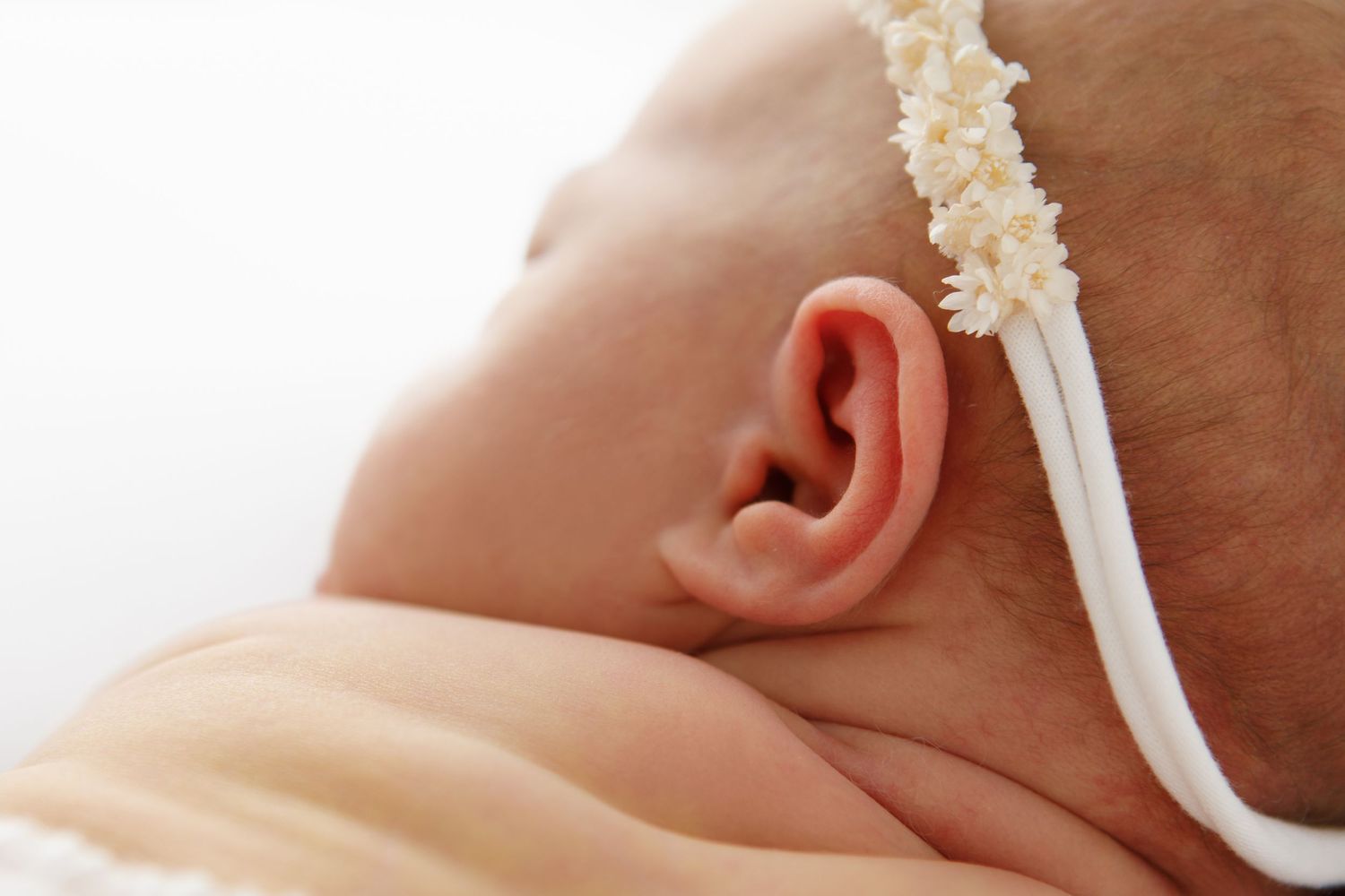 Macro shot of newborn features with delicate white headband.